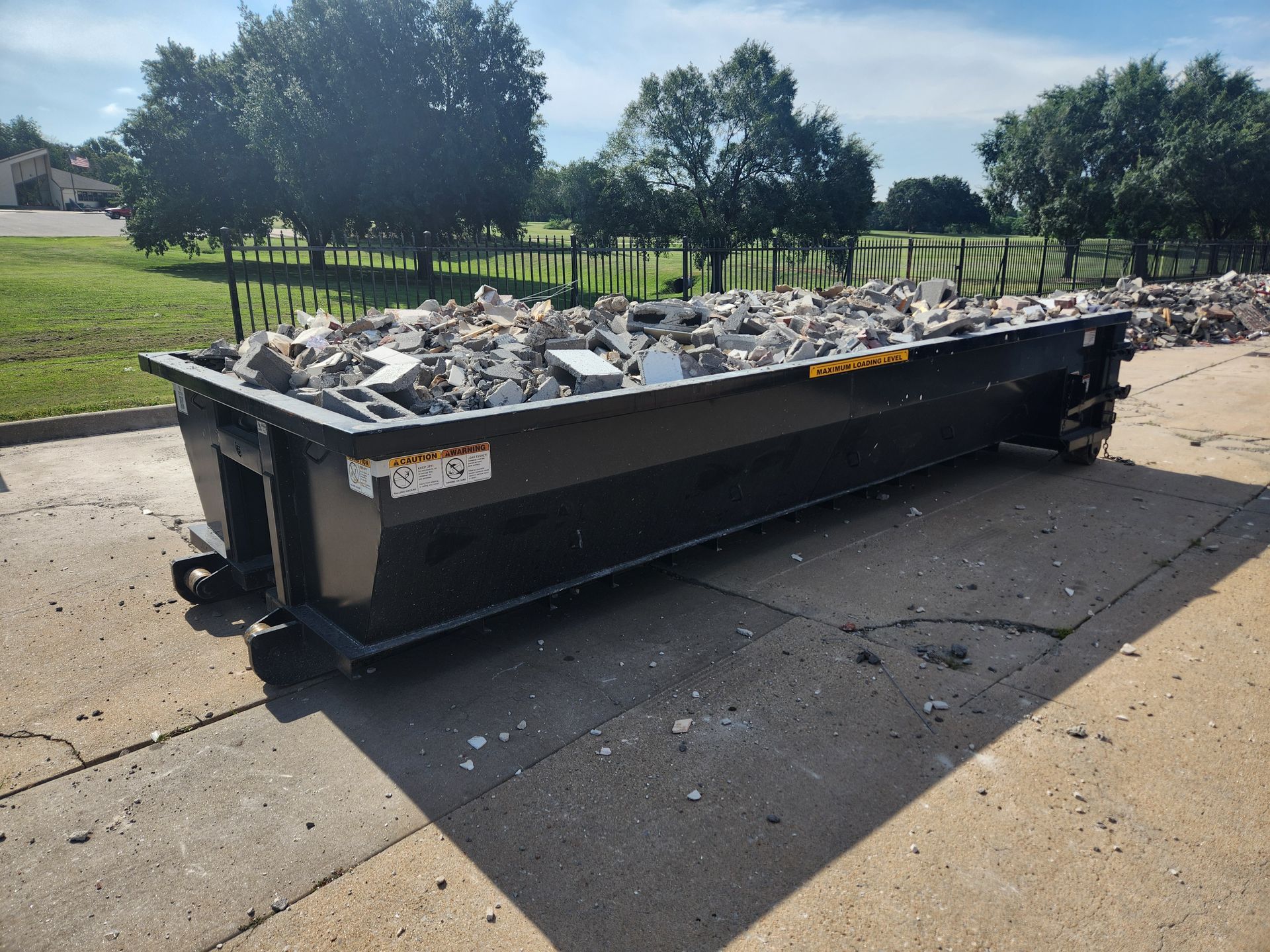 A dumpster filled with rocks is sitting on a sidewalk.