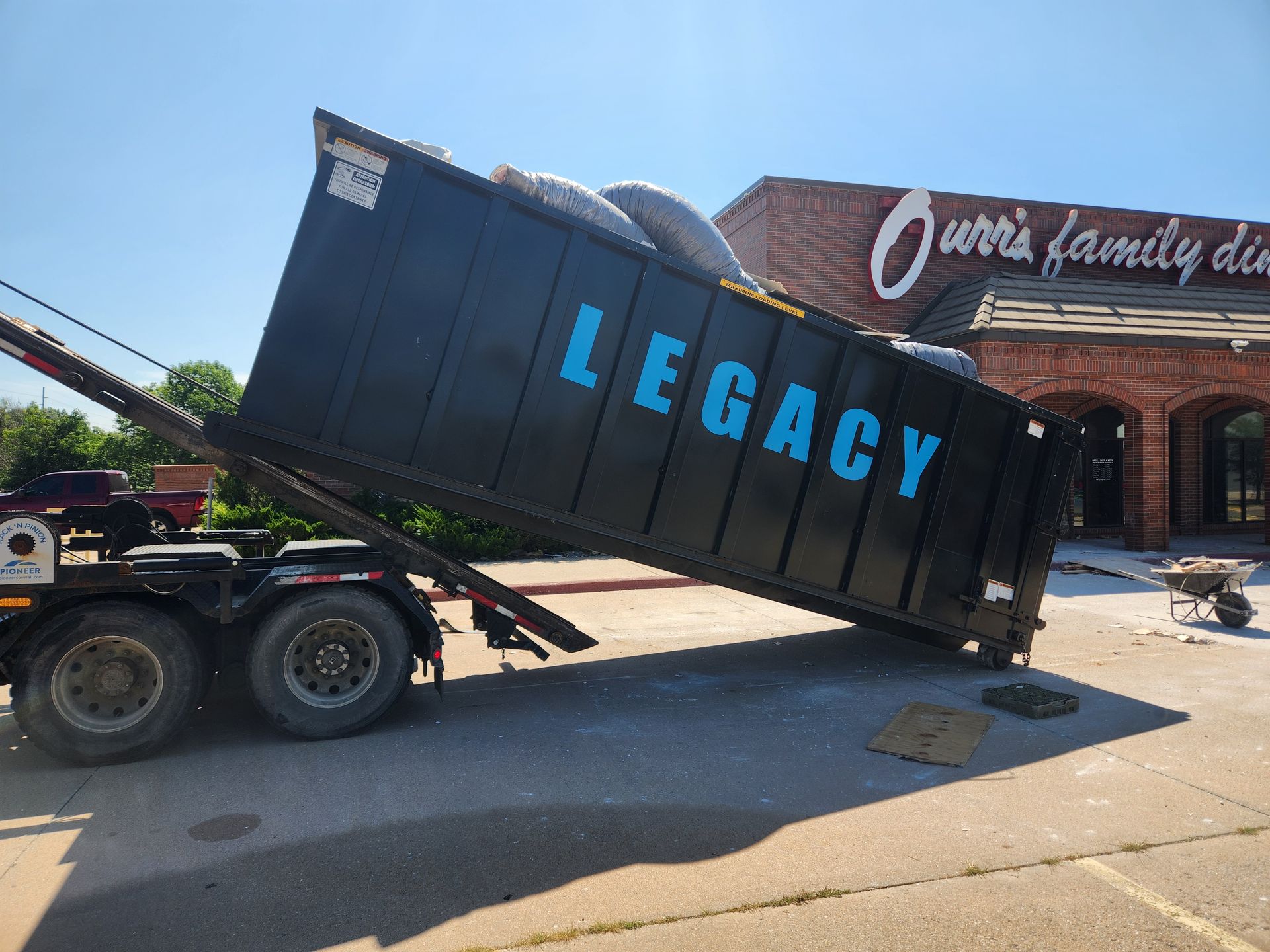 A dumpster with the word legacy on it is sitting in front of a building.