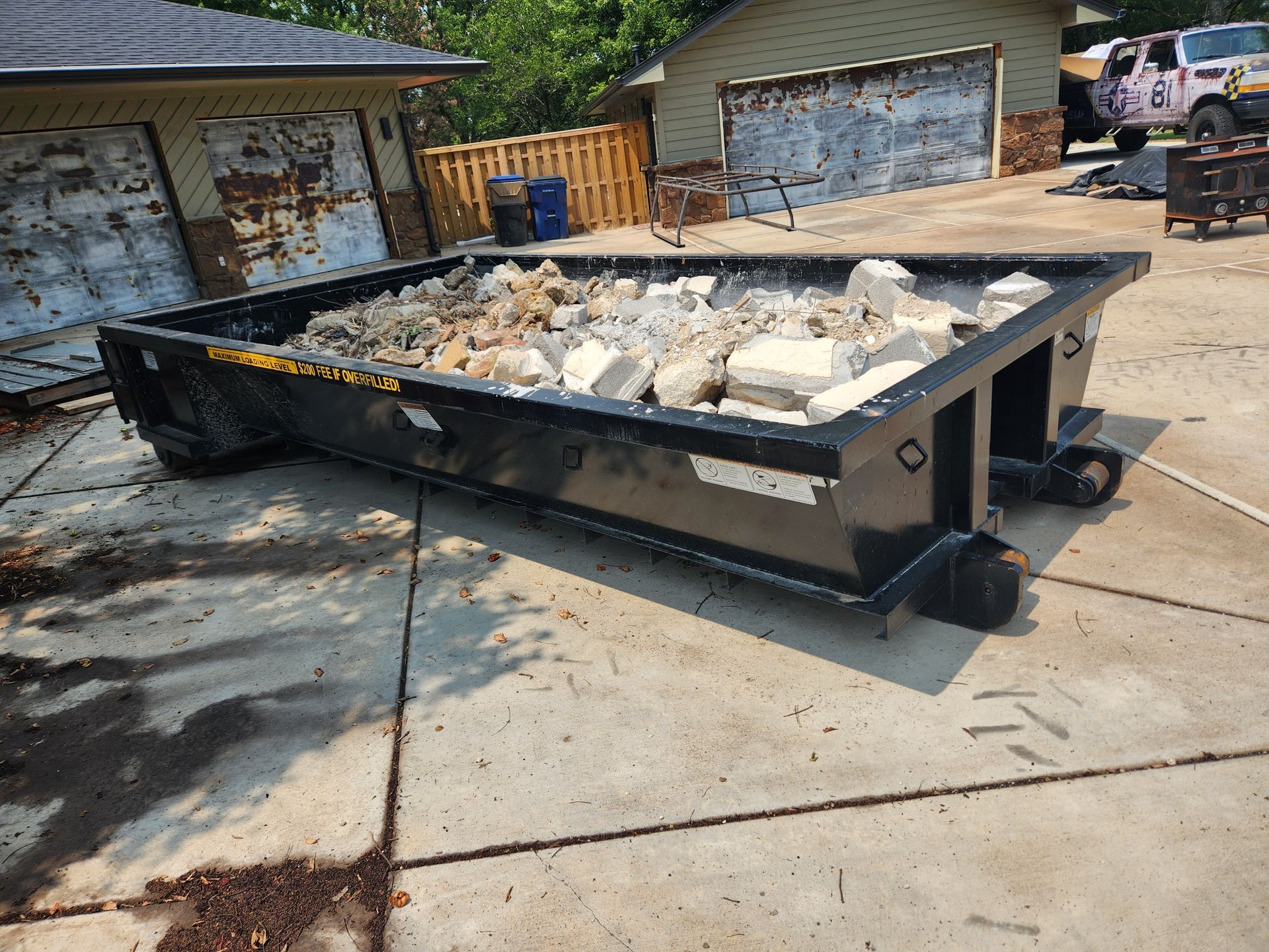 A dumpster filled with rocks is parked in front of a house.