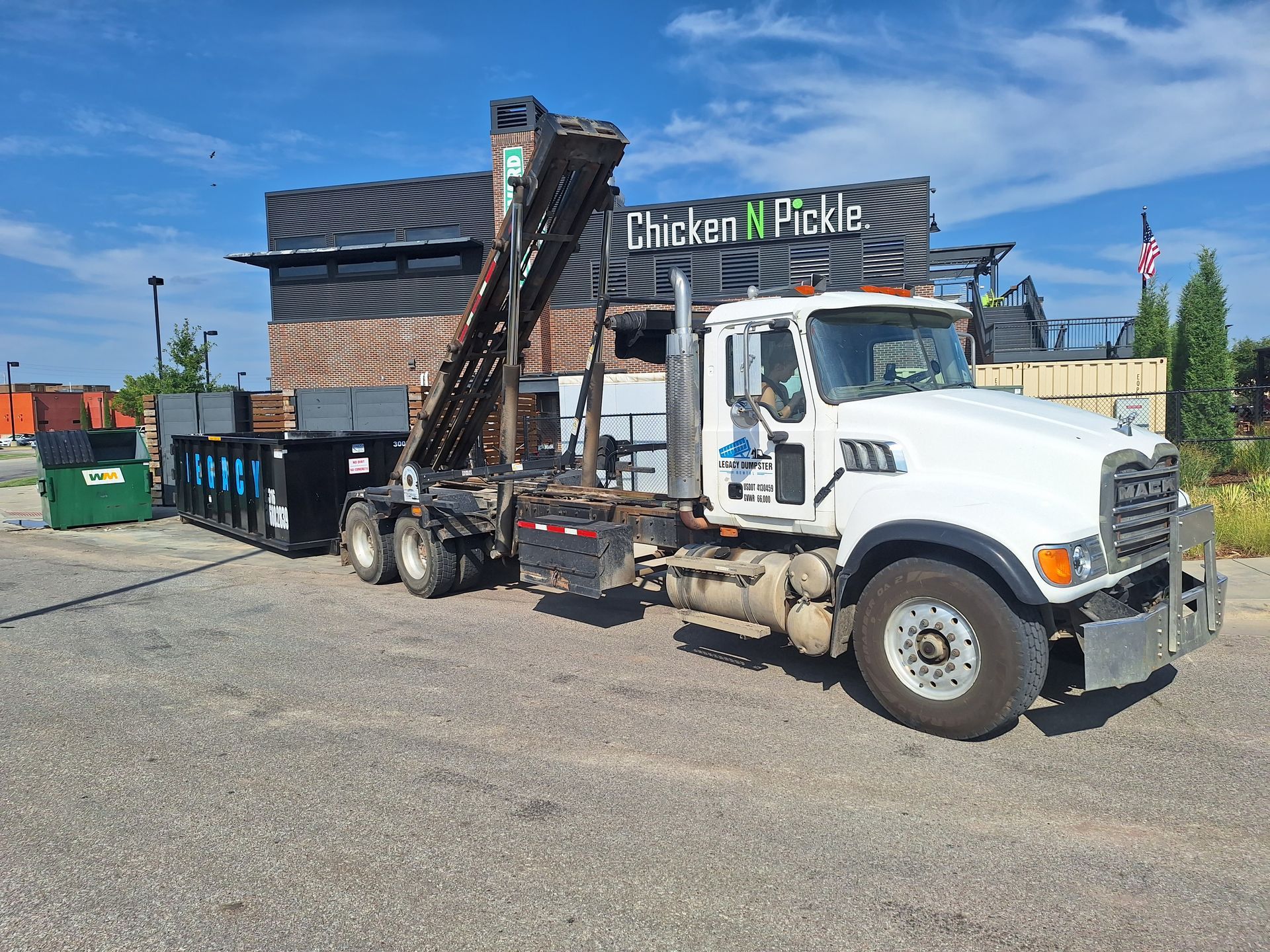 A green 15 yard dumpster is sitting in front of a black 15 yard dumpster wellington dumpster rentals
