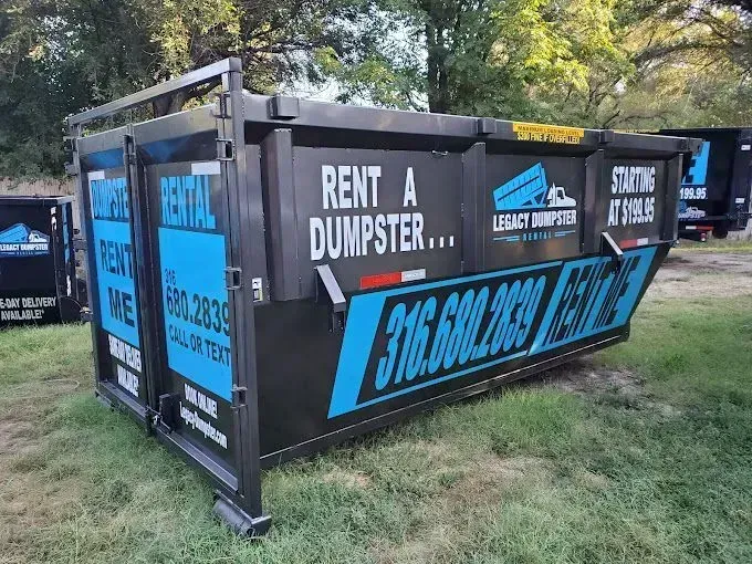 A green 15 yard dumpster is sitting in front of a black 15 yard dumpster wellington dumpsters