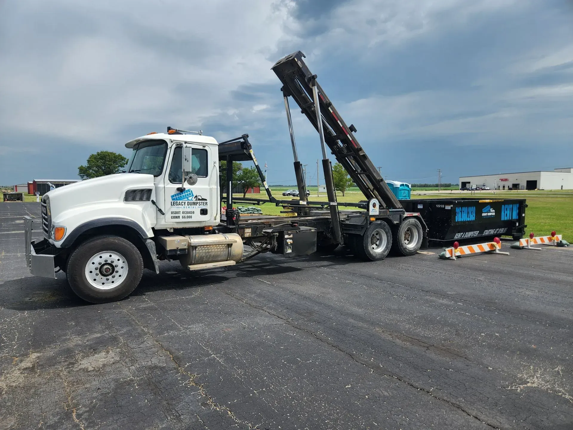 a dump truck is towing a dumpster in a field .