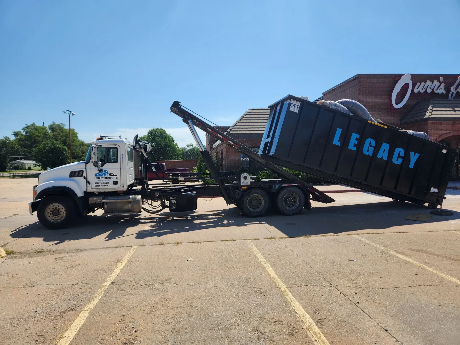 A green 15 yard dumpster is sitting in front of a black 15 yard dumpster haysville dumpsters