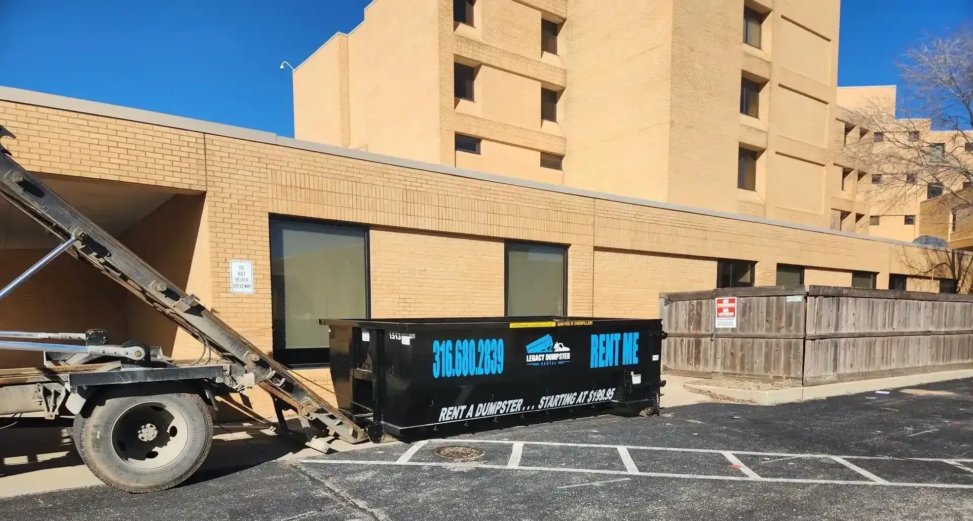 A 20 yard dumpster is parked in front of a brick building.
