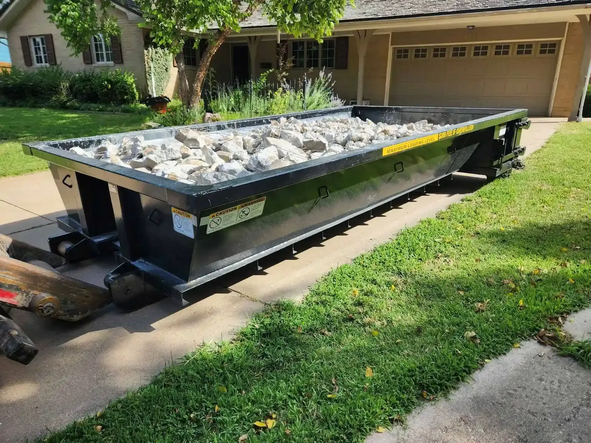 A dumpster is sitting on the sidewalk in front of a house.