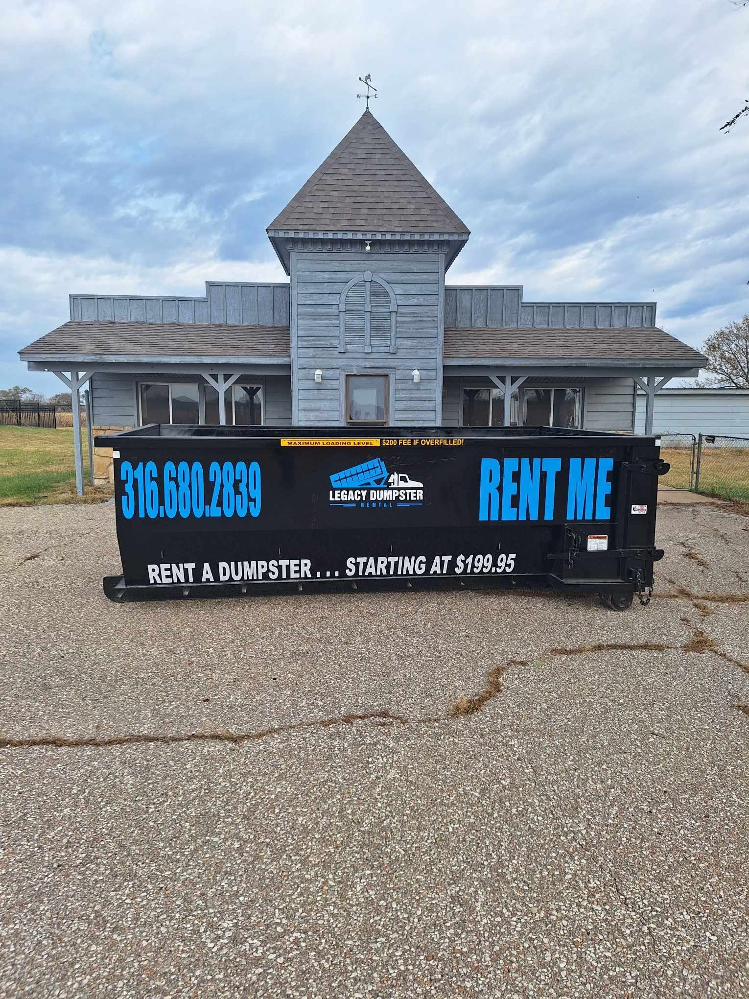 A dumpster is parked in front of a building that says rent me.