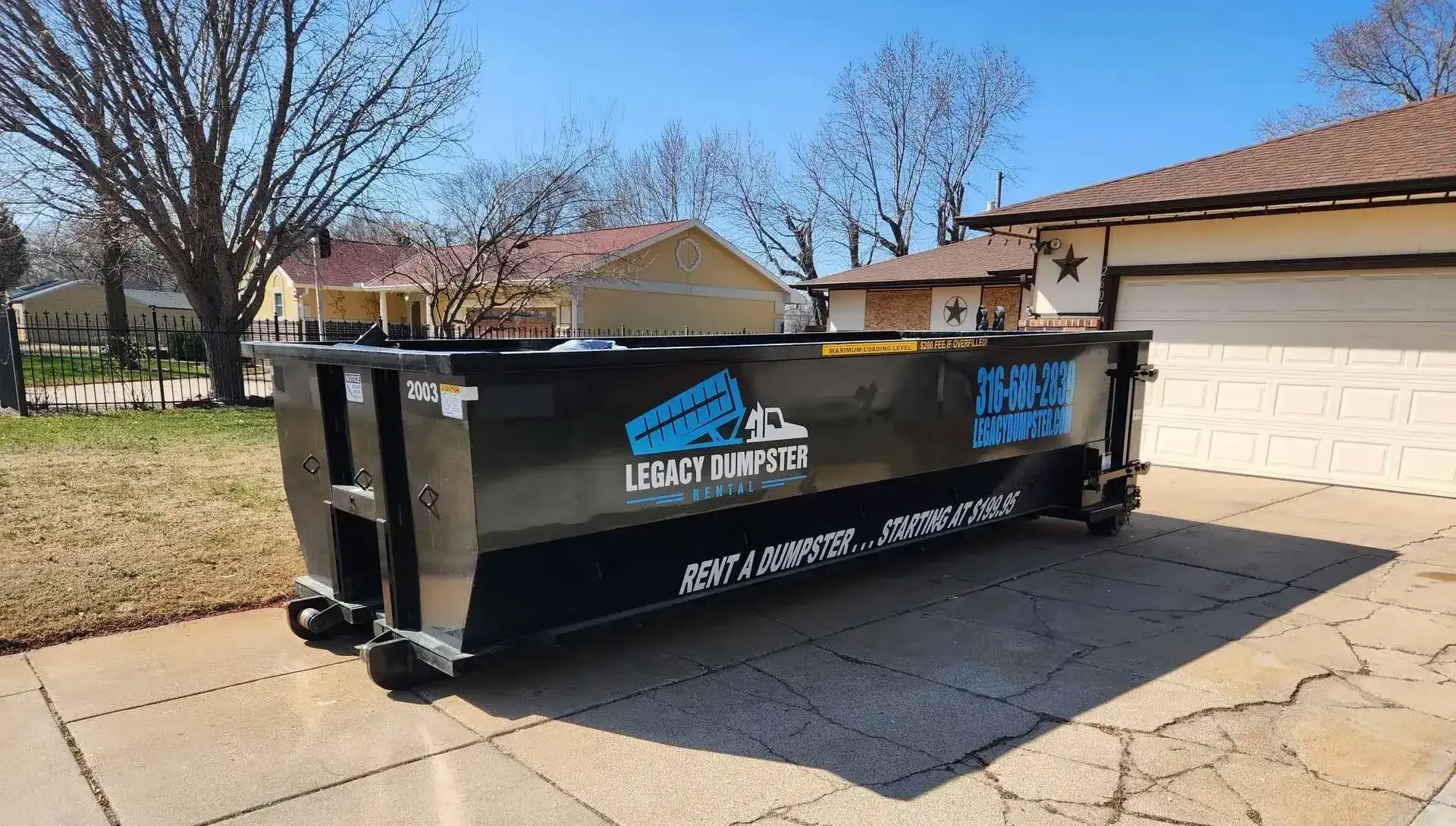 A 20 yard dumpster is parked in front of a house.