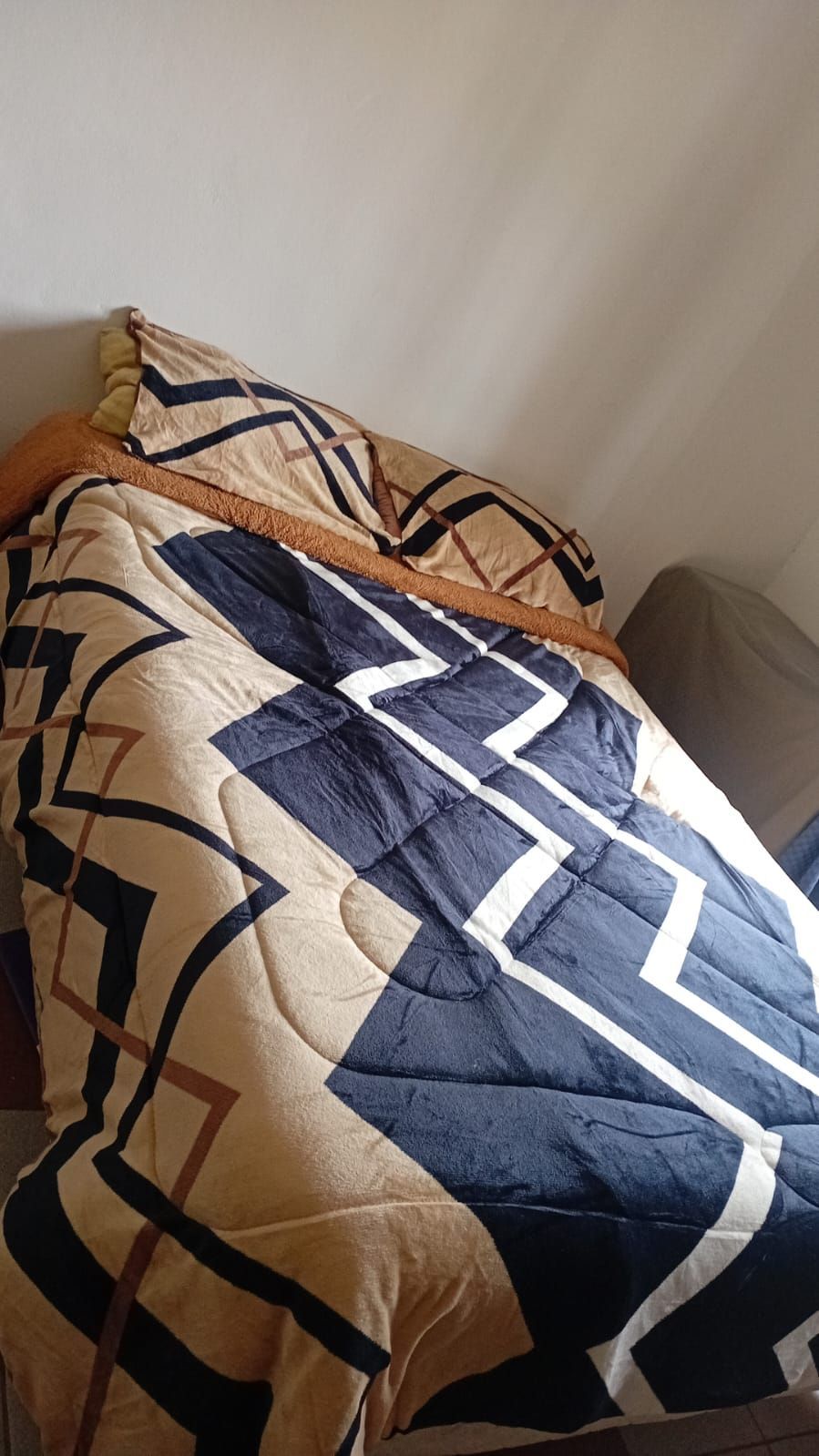 Una cama con una manta y almohadas encima en una habitación.