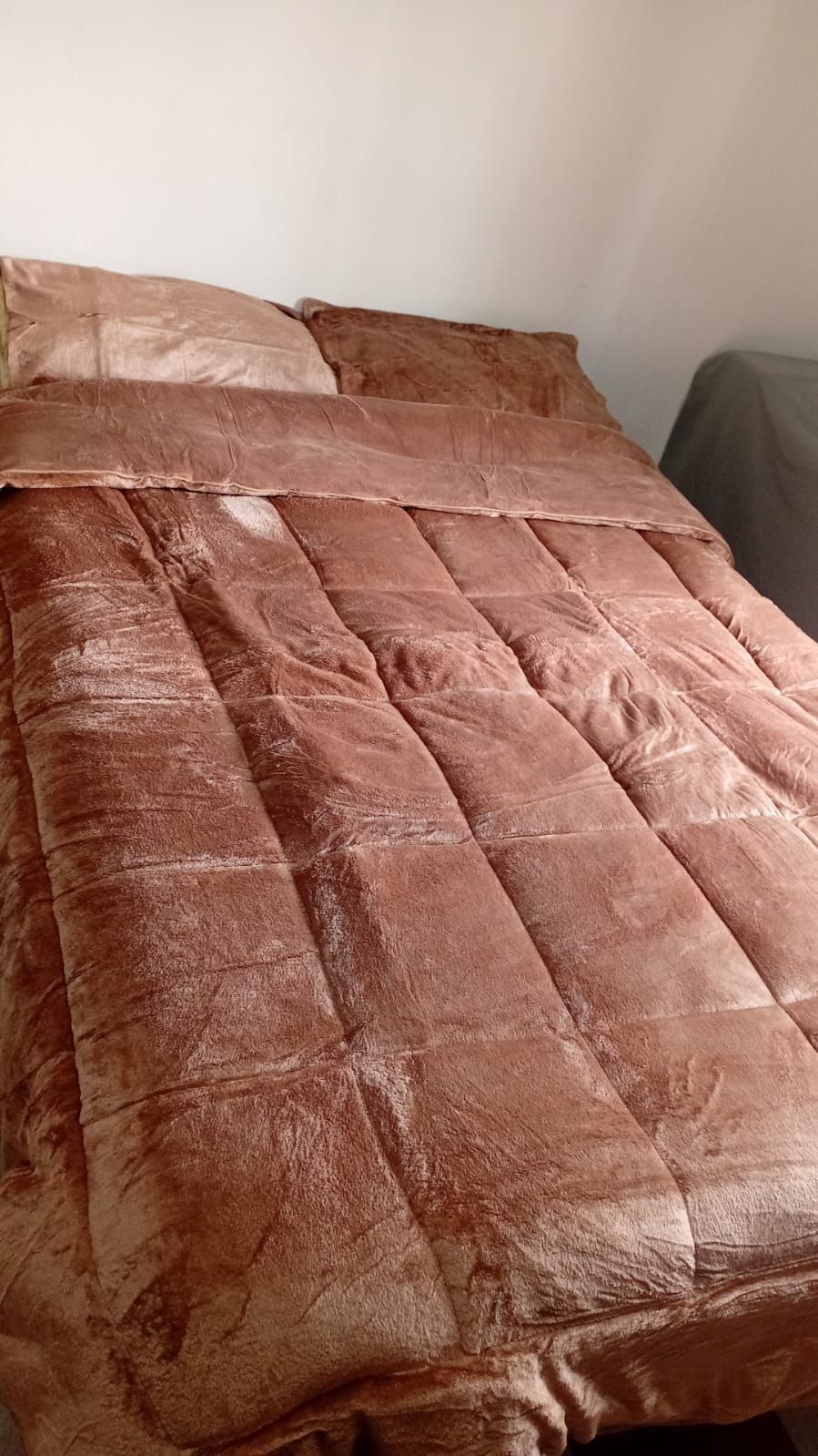 Una cama con un edredón marrón y almohadas en un dormitorio.