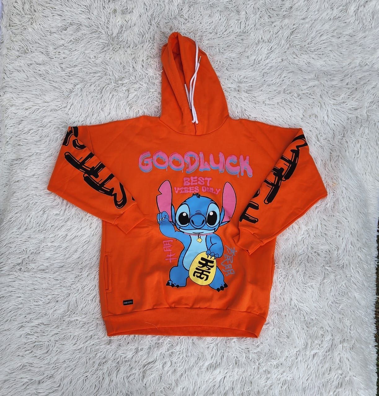 Una sudadera naranja con una costura que dice buena suerte.