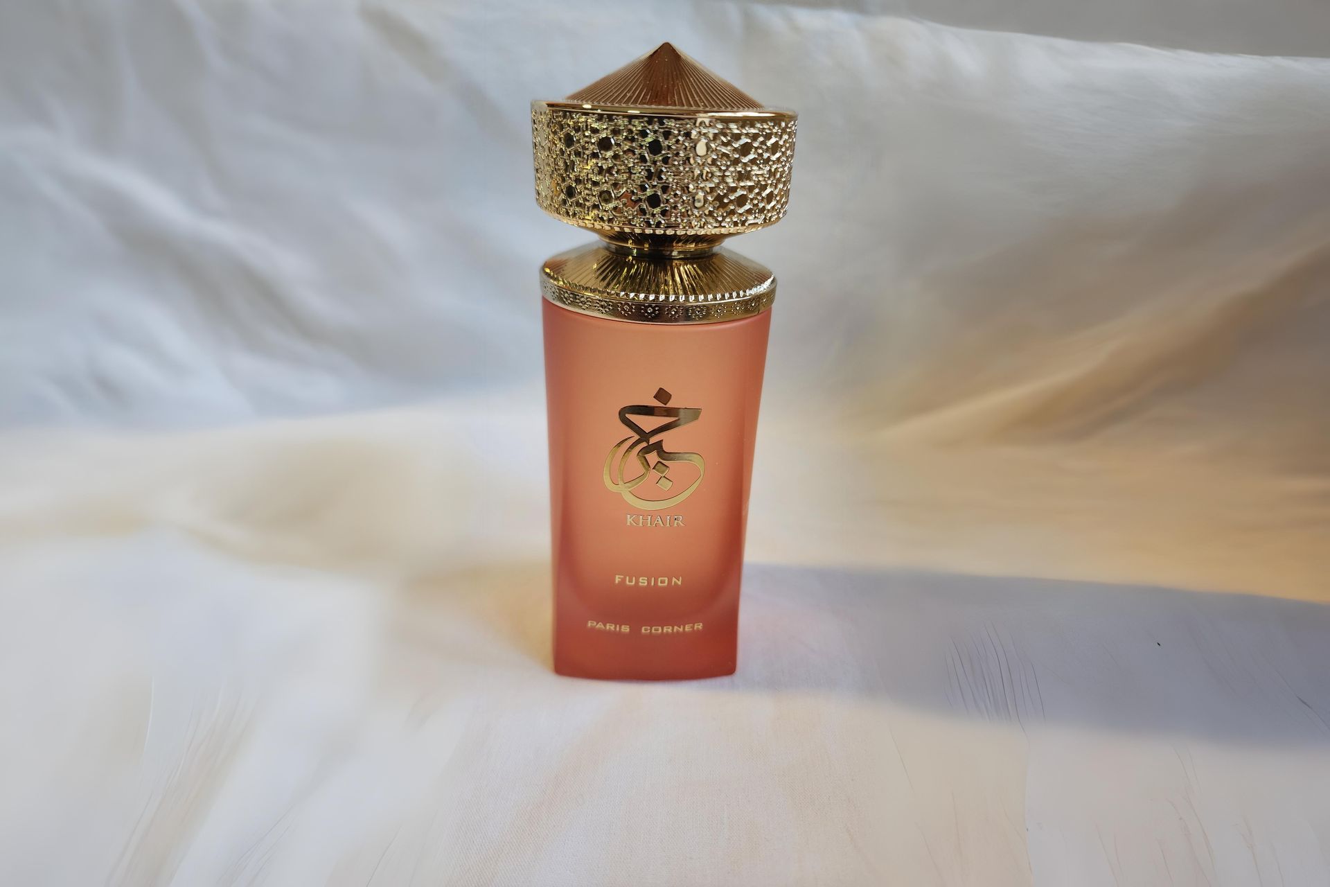Un frasco de perfume rosa con tapón dorado.