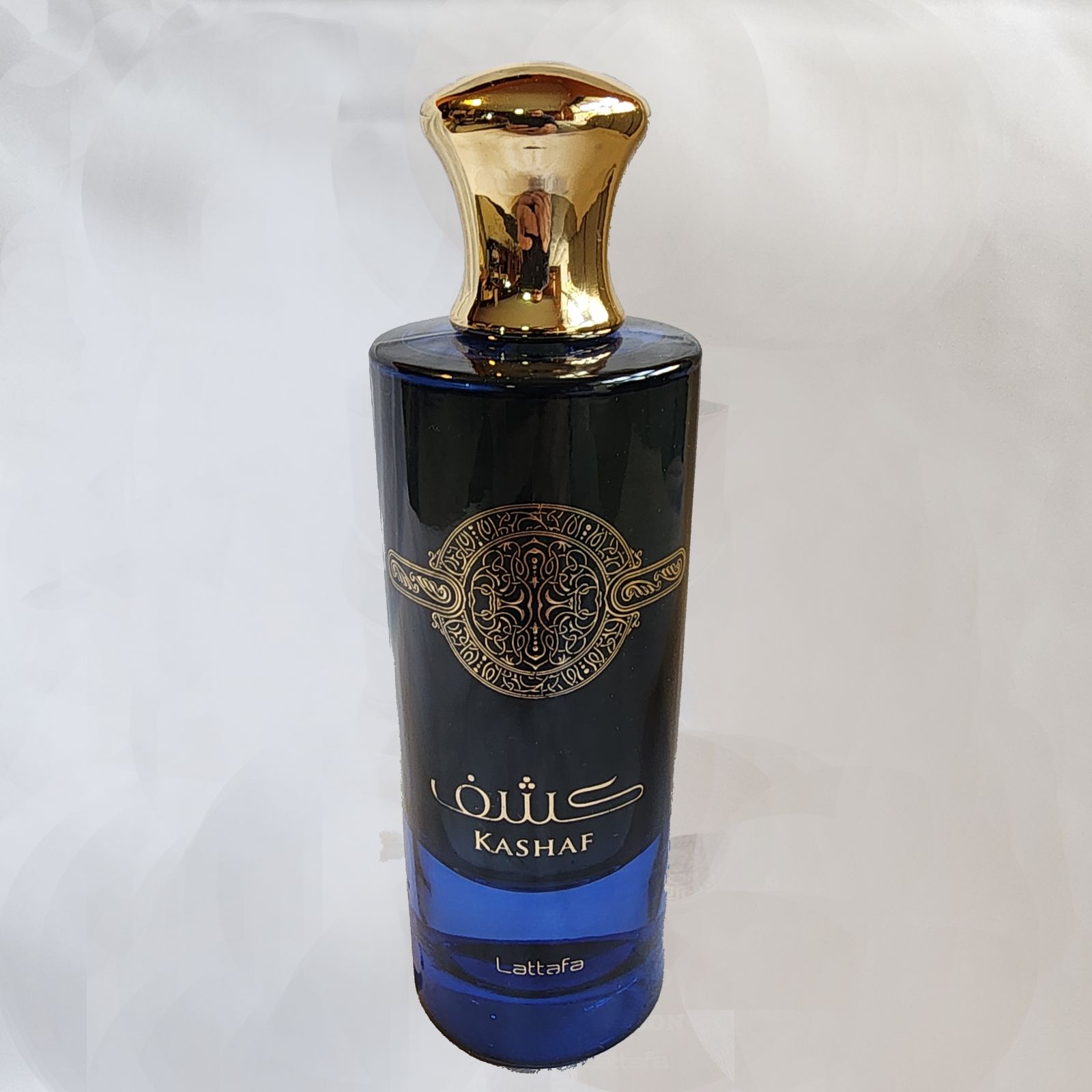 Un frasco de perfume con un tapón dorado sobre una superficie blanca.