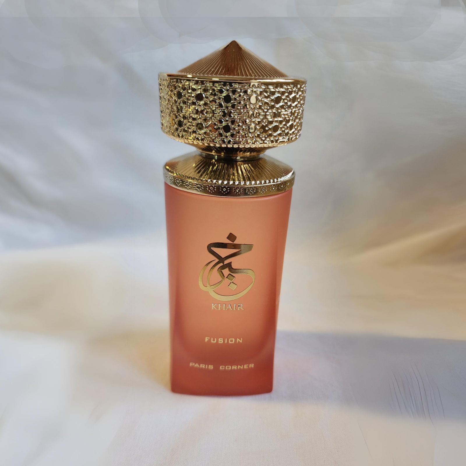Una botella de perfume de fusión reposa sobre una superficie blanca.