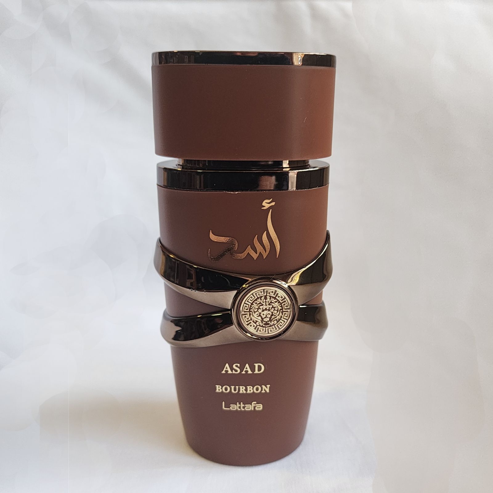 Una botella de perfume Asad se encuentra sobre una superficie blanca.