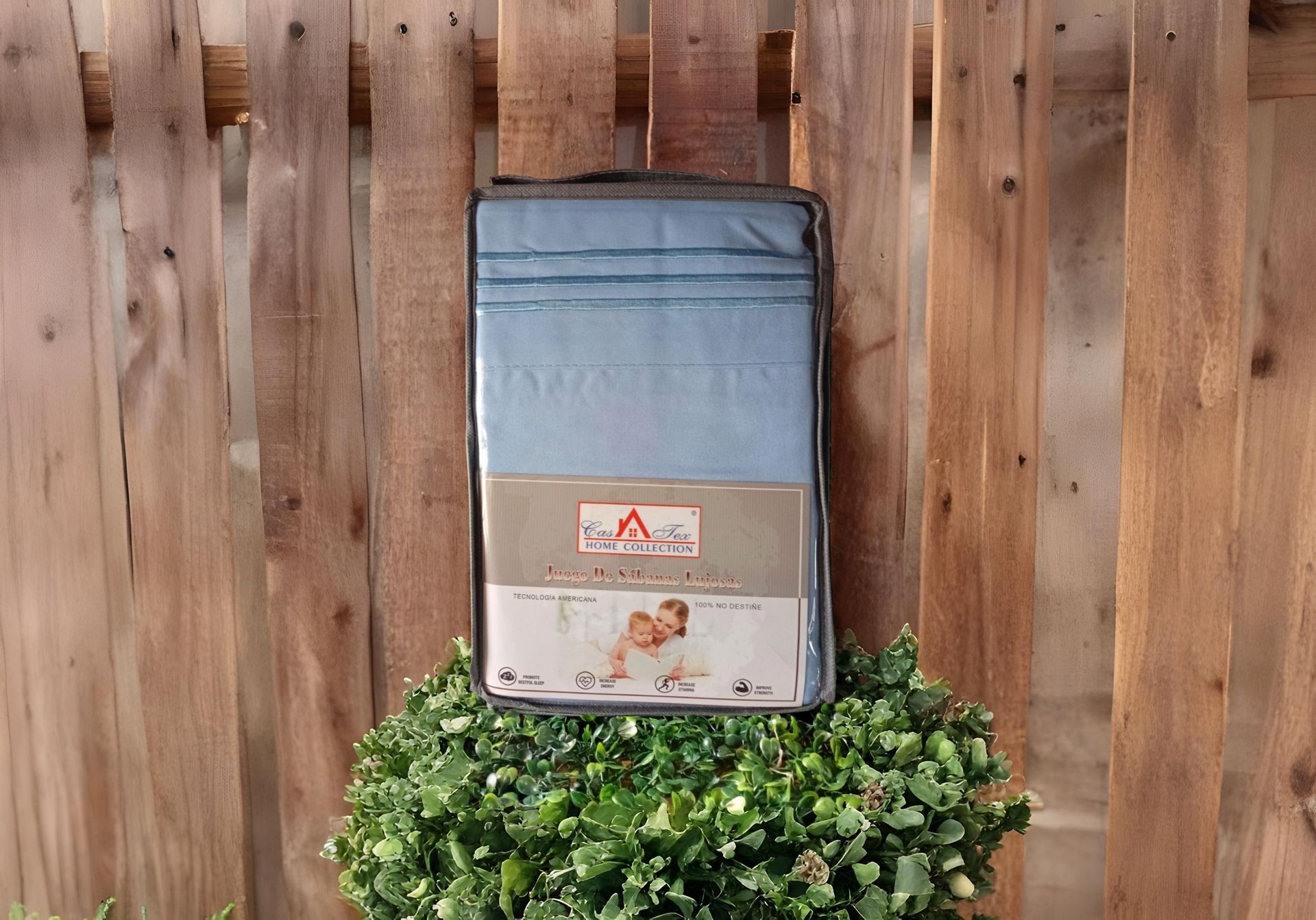 Una manta azul cuelga de una valla de madera al lado de una planta.