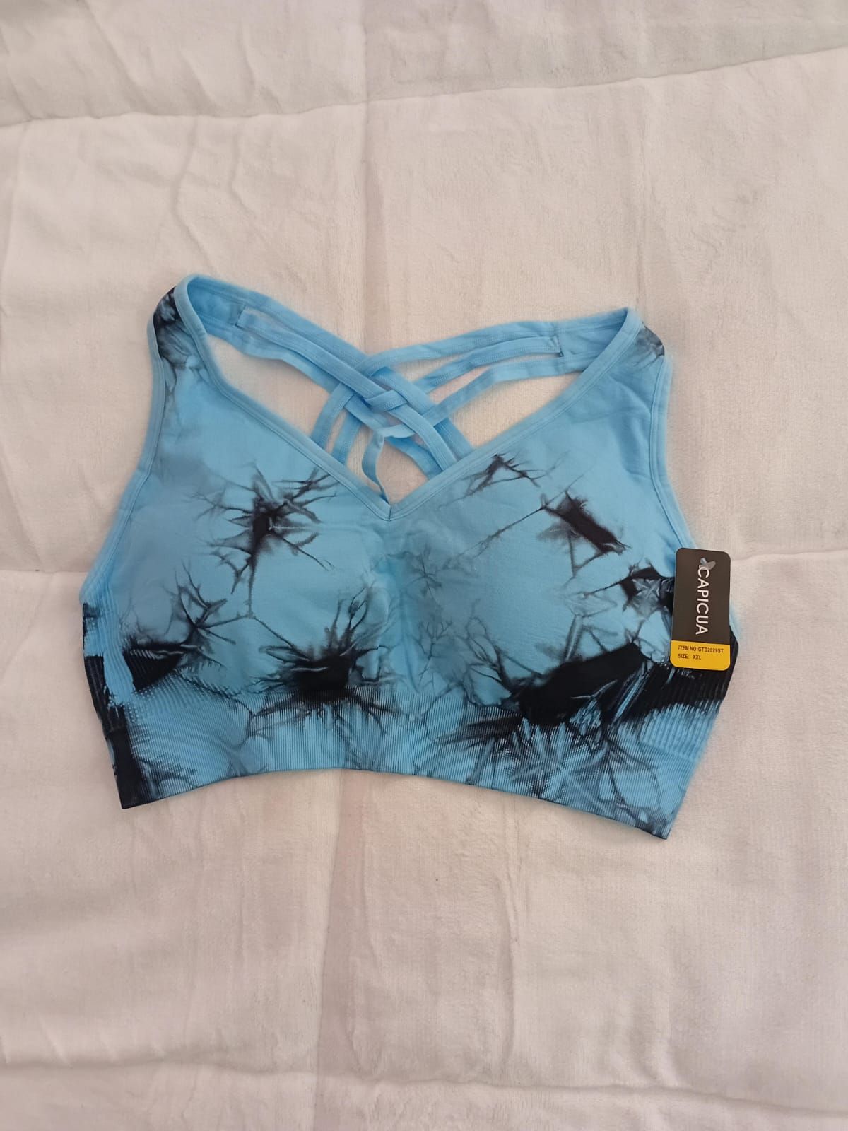 Un sujetador deportivo rosa y negro está sobre una cama.