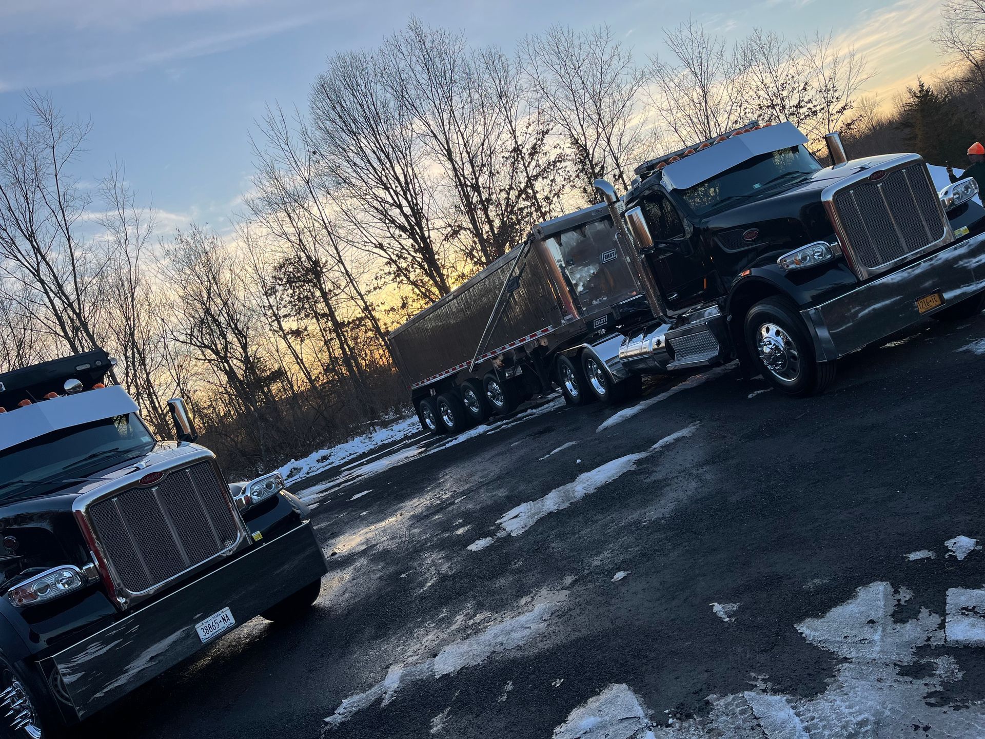 Two semi trucks are parked next to each other on the side of the road.