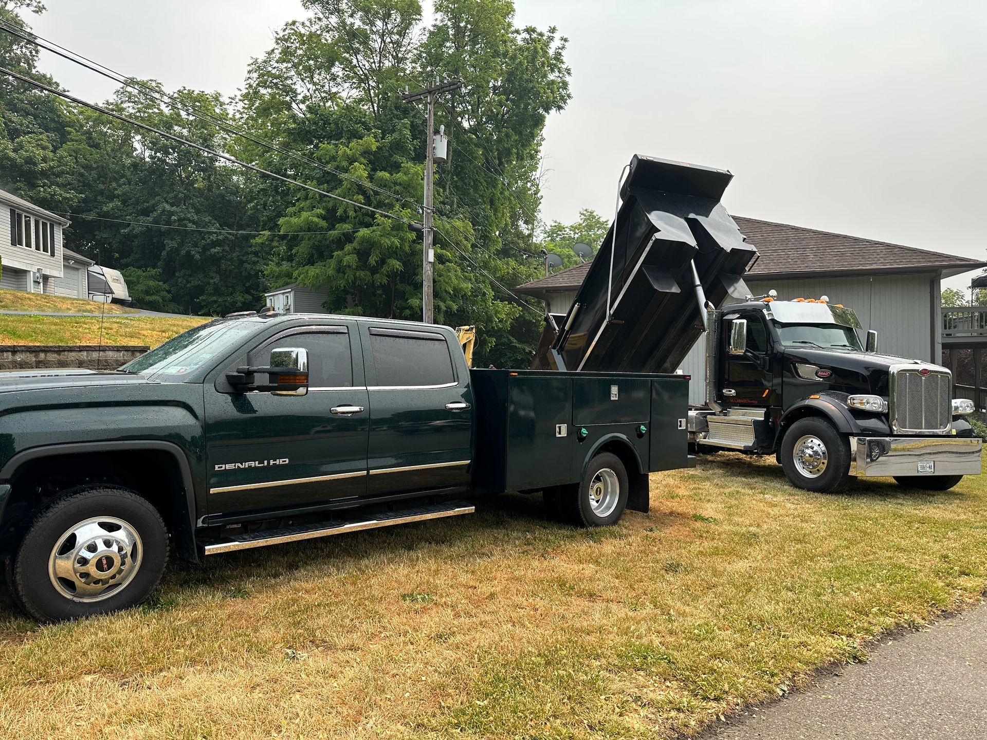 Two dump trucks are parked next to each other in a yard.