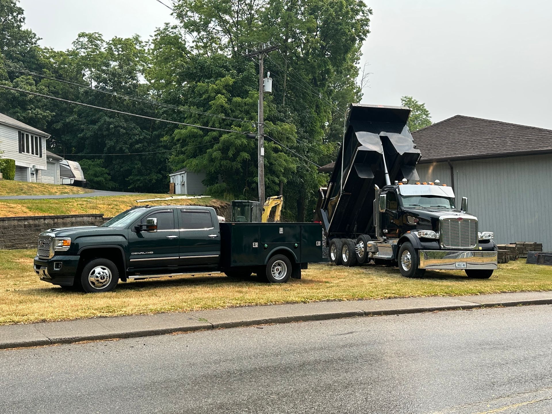 Two dump trucks are parked next to each other on the side of the road.