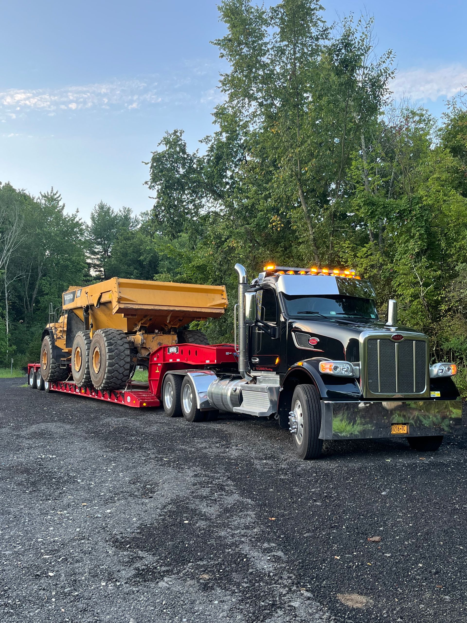 A semi truck is carrying a dump truck on a trailer.