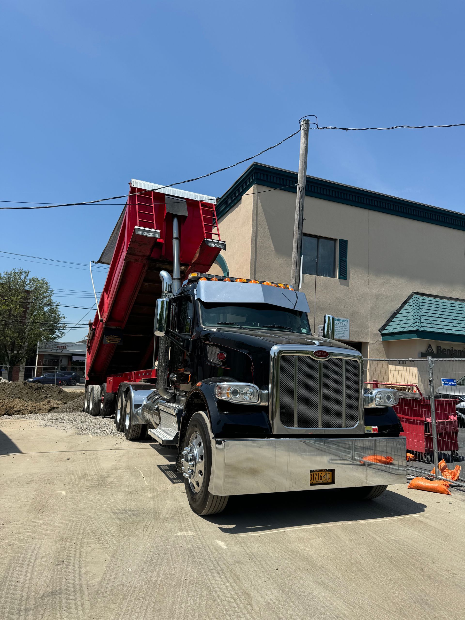 A dump truck is parked in a parking lot in front of a building.