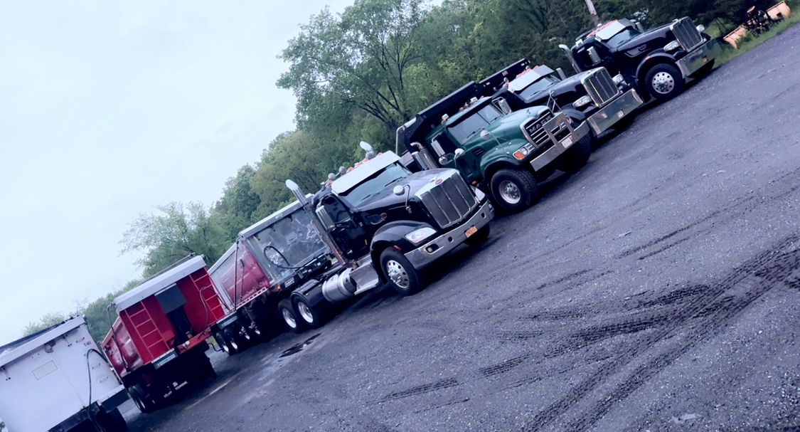 A row of semi trucks are parked in a parking lot.