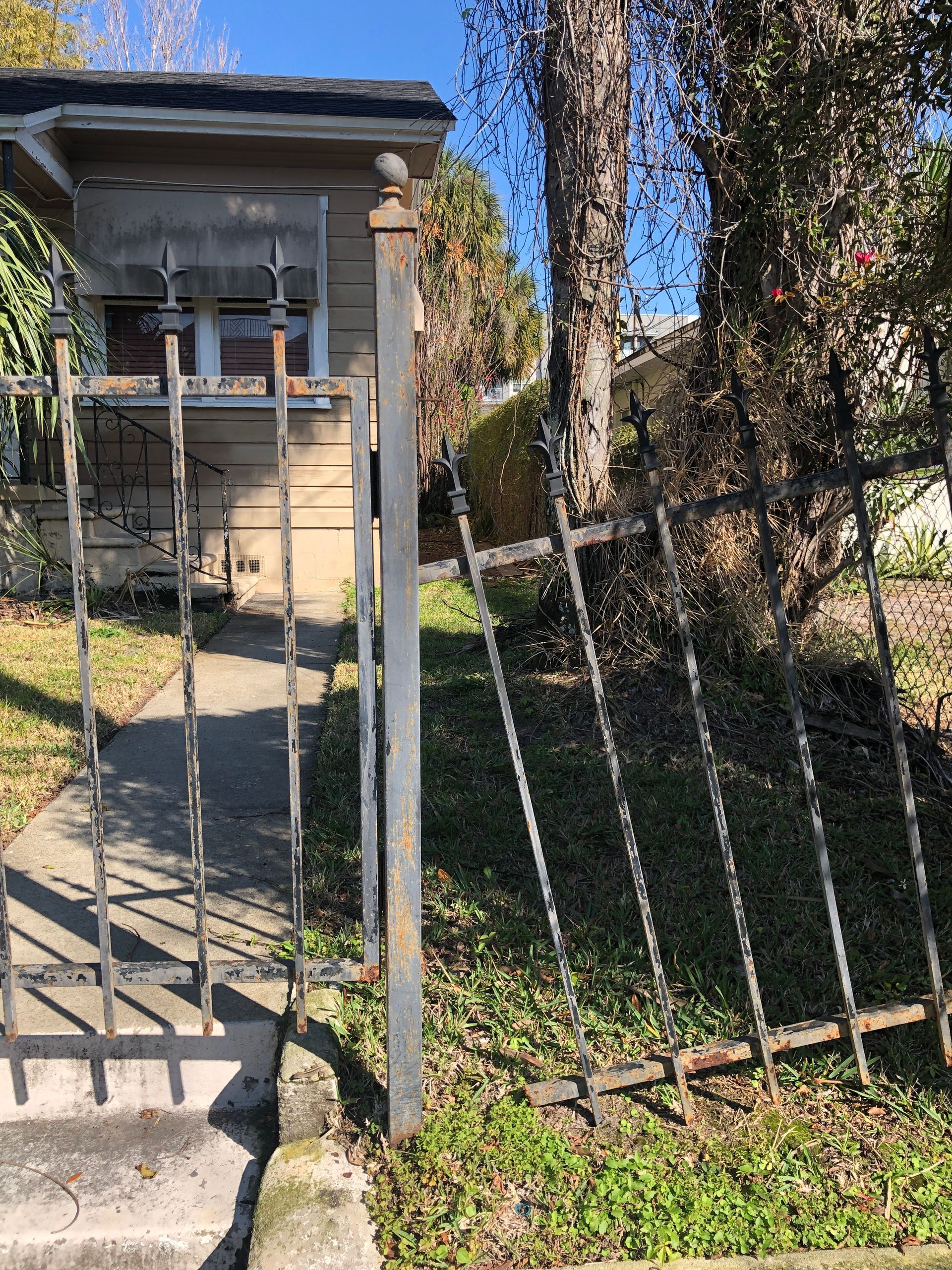 A rusted iron fence in front of a single-family home in South Tampa