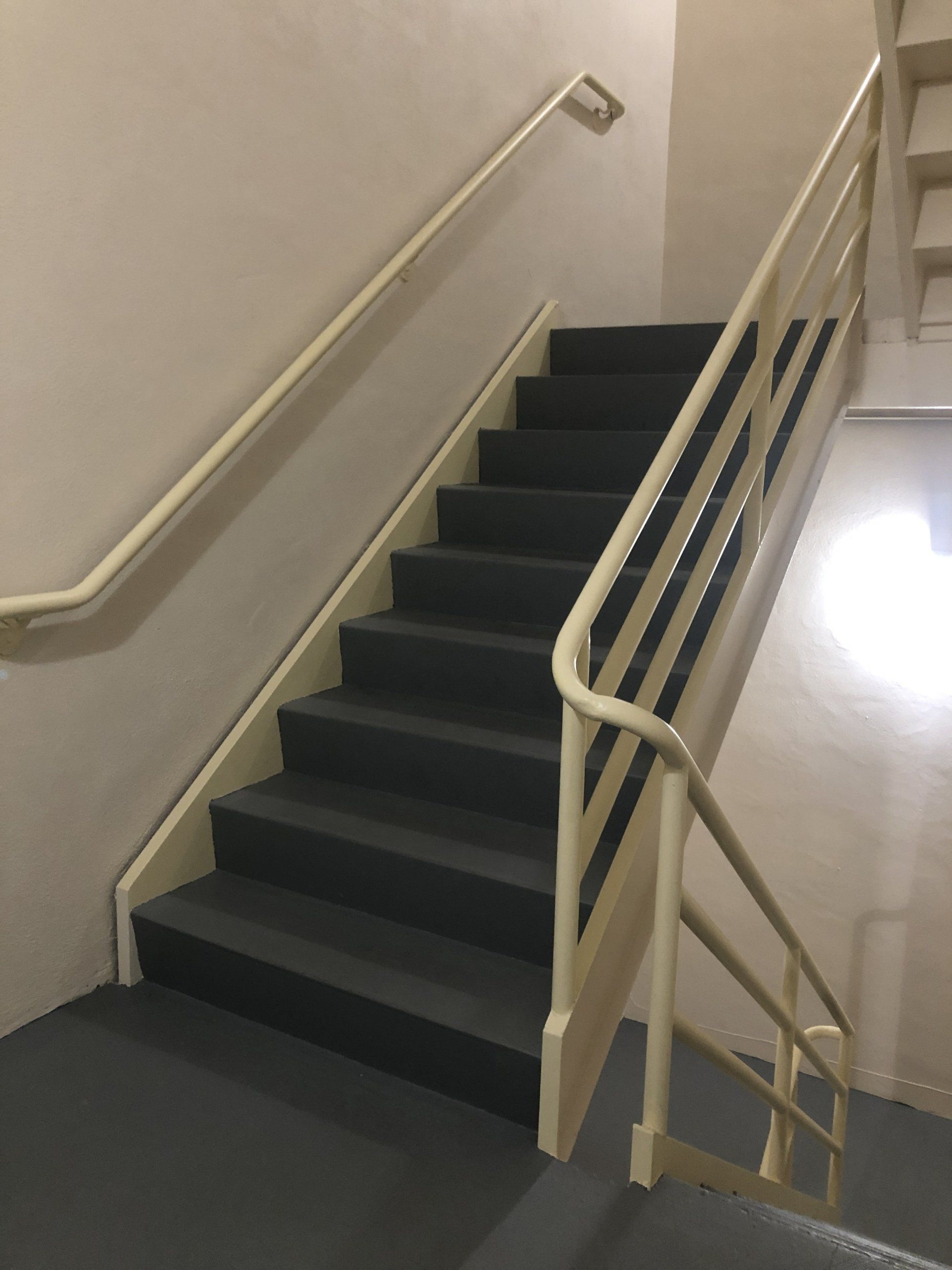indoor office building stairwell with metal handrails leading to an exit