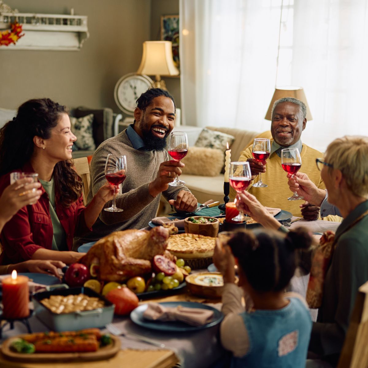 A group of people are sitting around a table eating food and drinking wine.