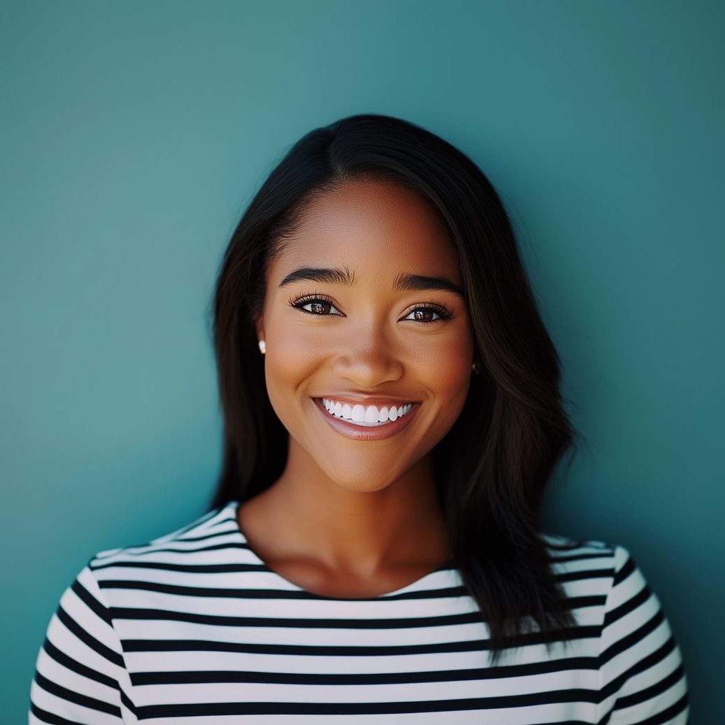 A woman in a striped shirt is smiling in front of a blue wall