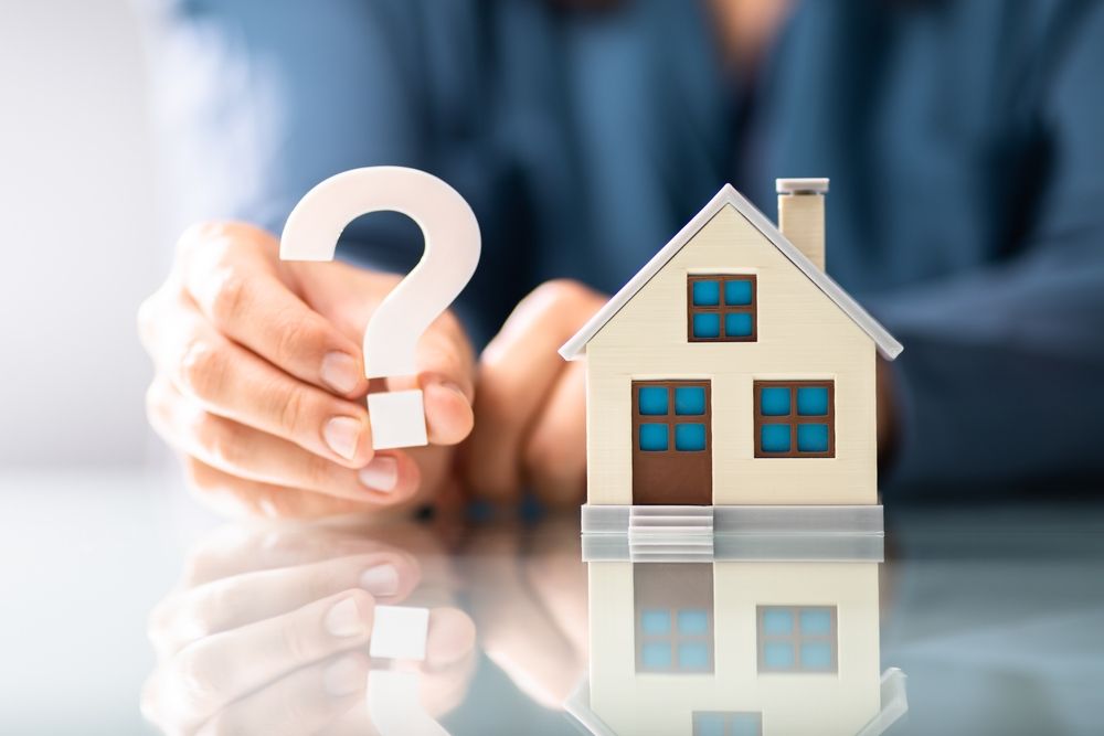 man holding wooden home and wooden question mark