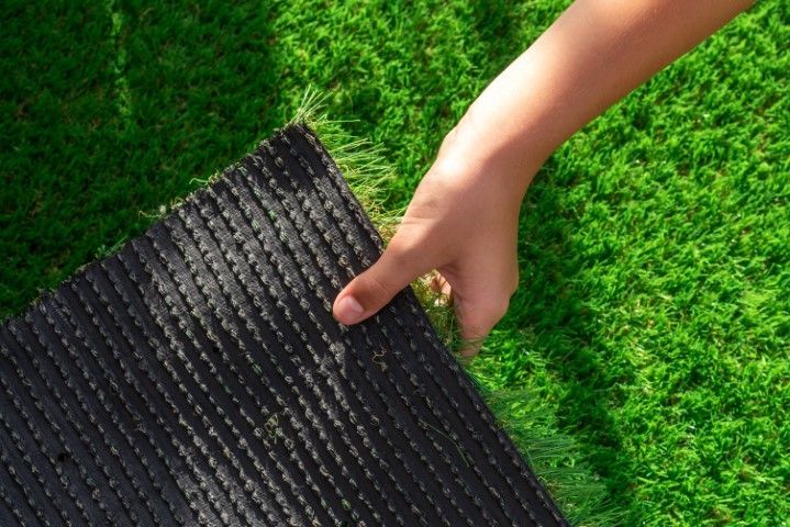 A hand pulling back artificial grass