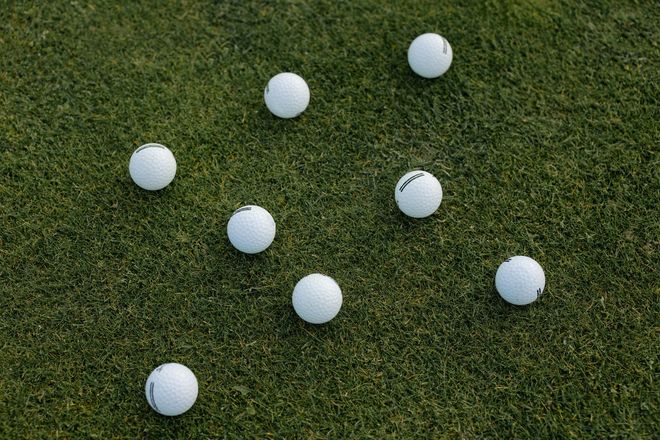 Synthetic turf with a few golf balls scattered on it. 