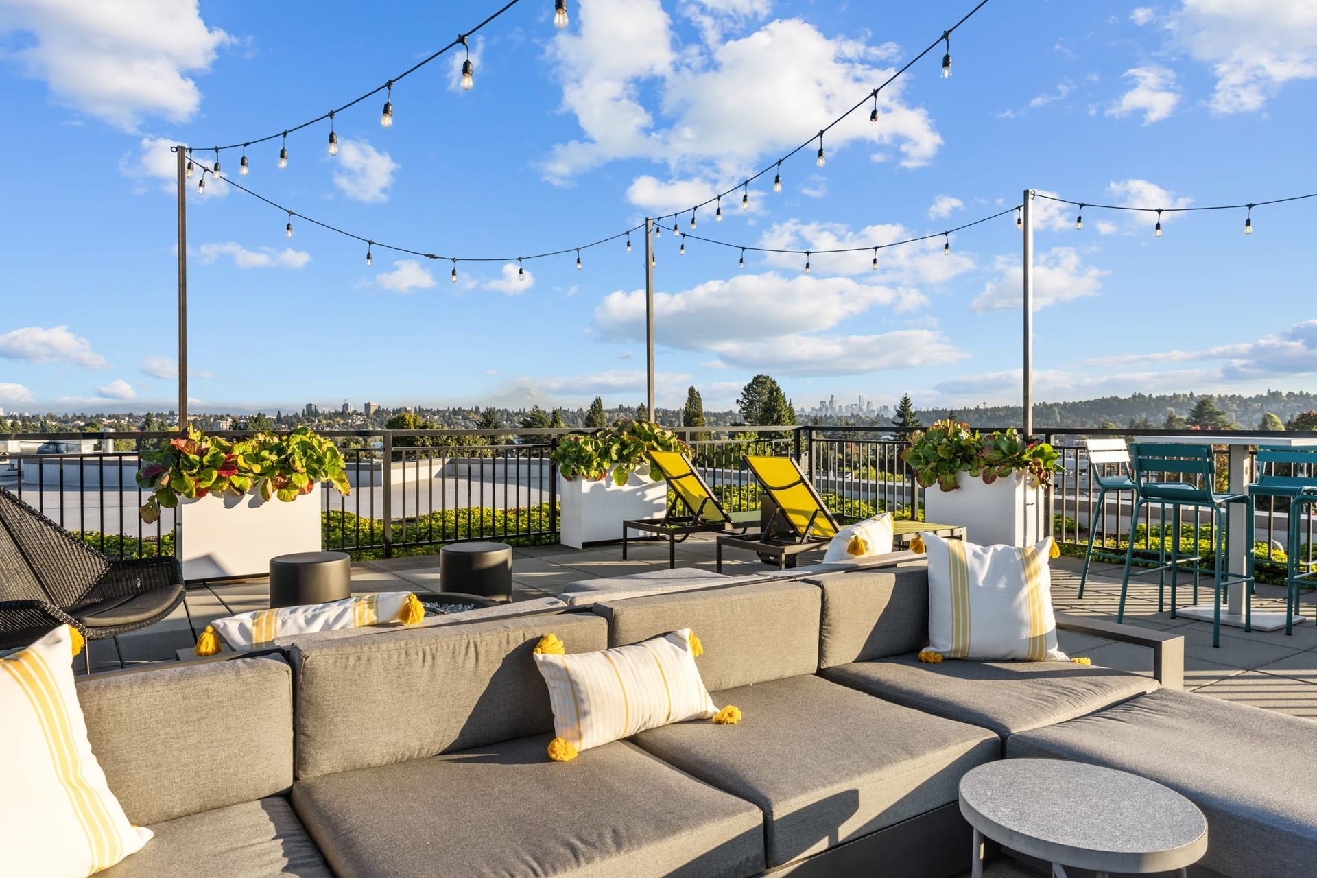 A rooftop patio with a couch , chairs , and a table at CREW Apartments in Seattle, WA.