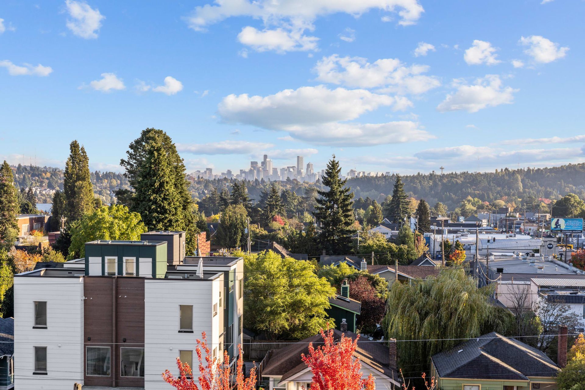 An aerial view of a city with a building in the foreground and a city skyline in the background at CREW Apartments in Seattle, WA.