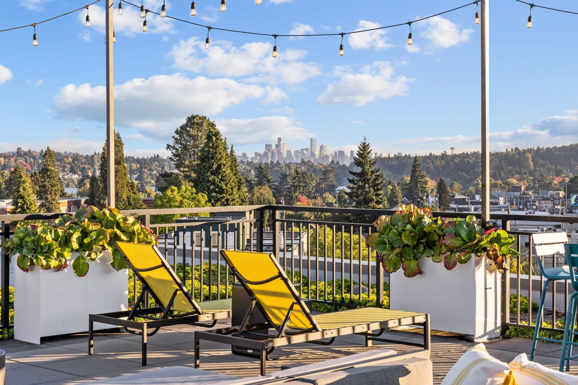 There are two yellow lounge chairs on the balcony with a view of the city at CREW Apartments in Seattle, WA.