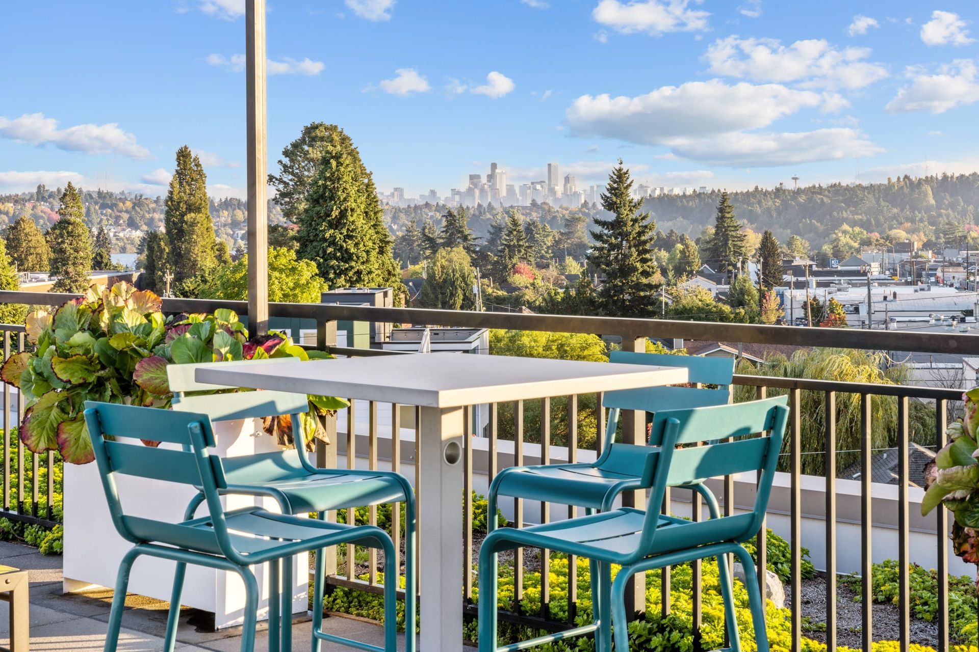 A table and chairs on a balcony overlooking a city at CREW Apartments in Seattle, WA.