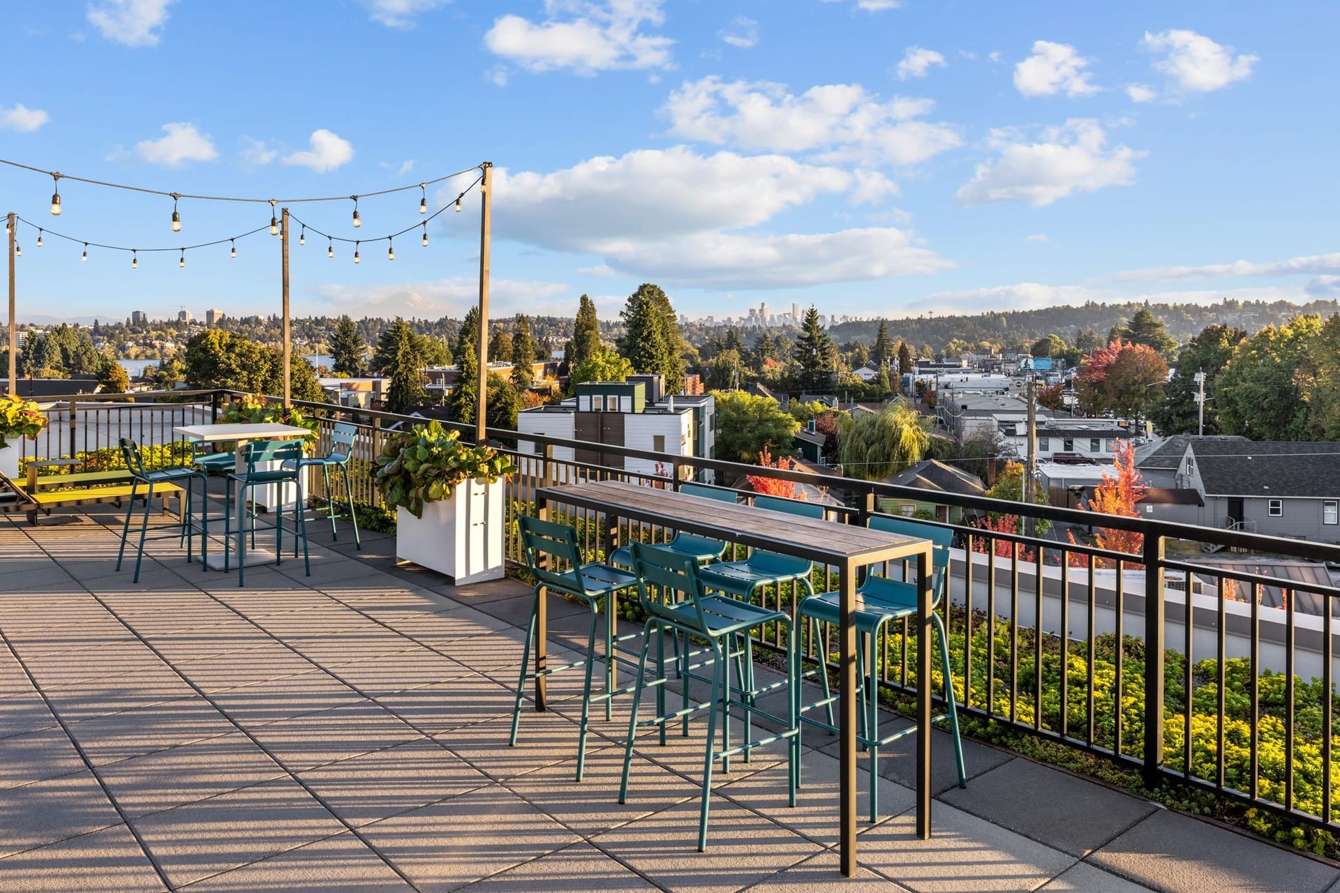 A rooftop deck with a table and chairs and a view of a city at CREW Apartments in Seattle, WA.