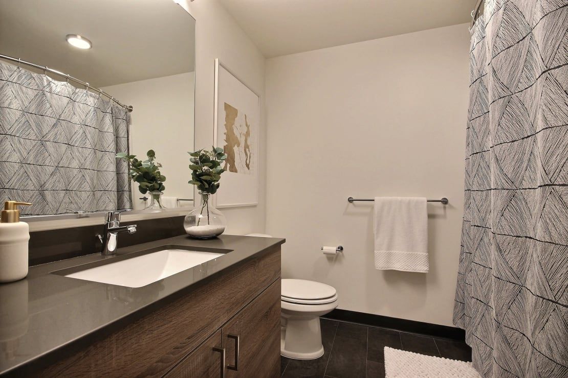 A bathroom with a sink , toilet , shower and mirror at CREW Apartments in Seattle, WA.