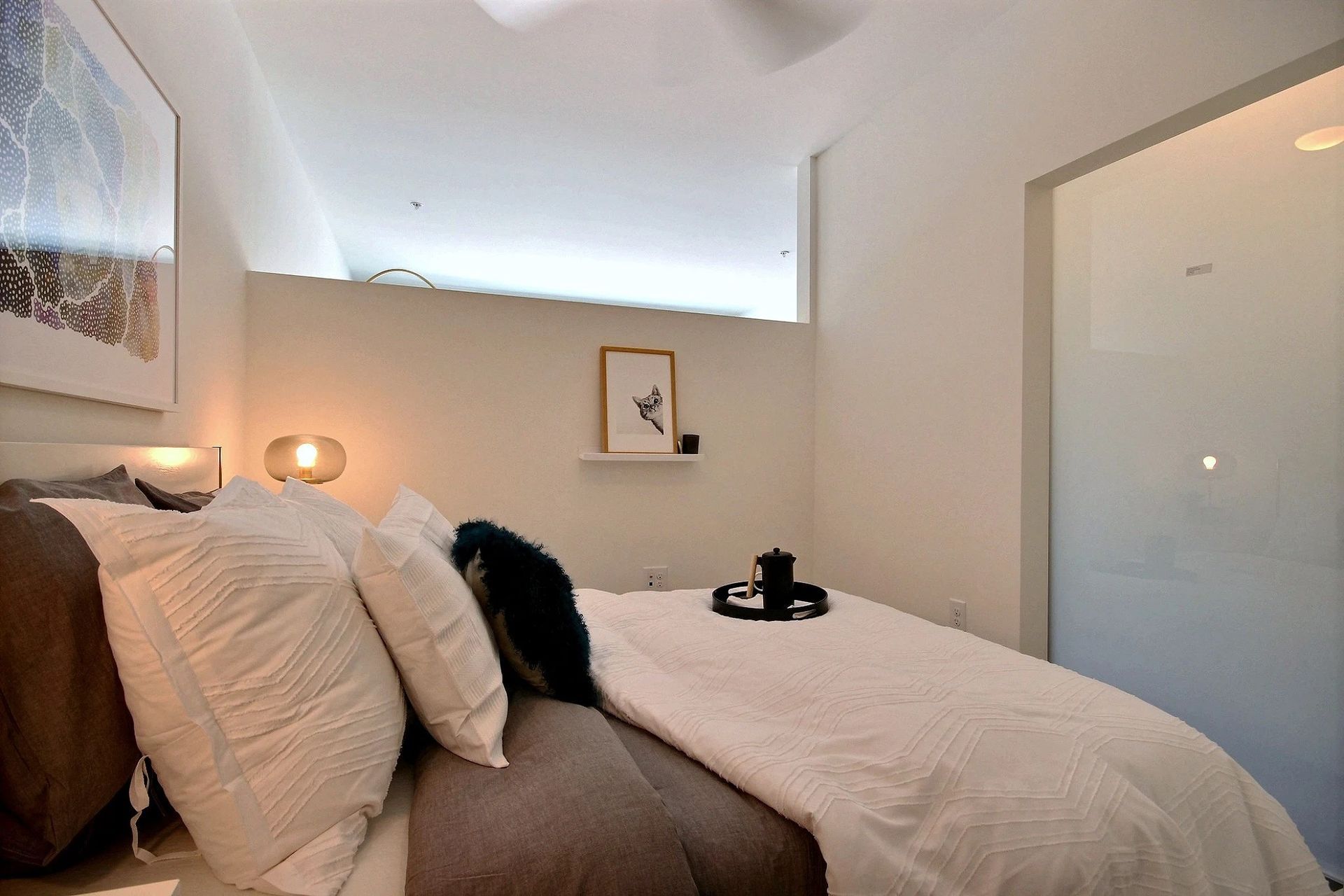 A bedroom with a bed , pillows and a picture on the wall at CREW Apartments in Seattle, WA.