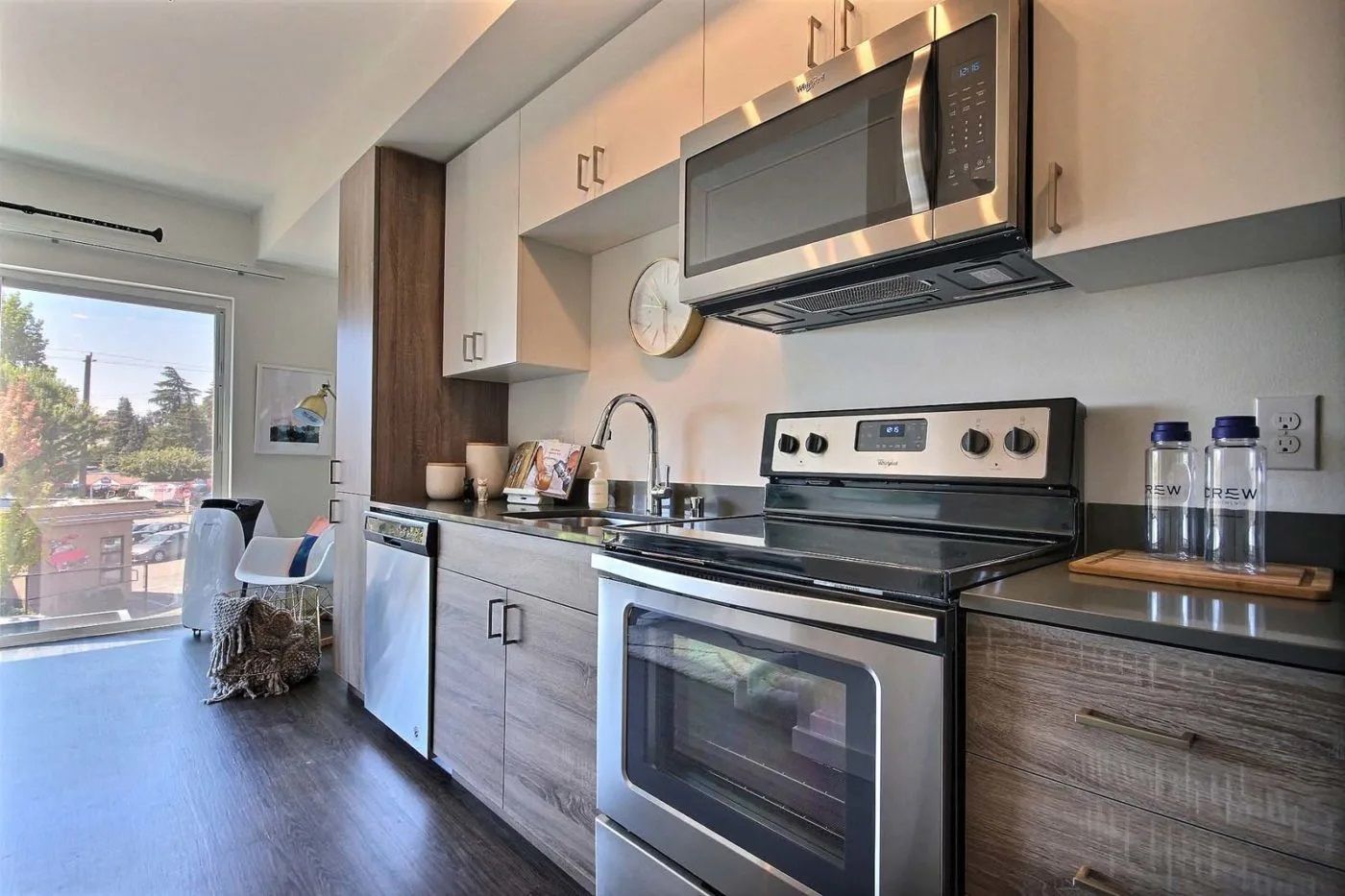 A kitchen with a stove , microwave , sink and cabinets at CREW Apartments in Seattle, WA.