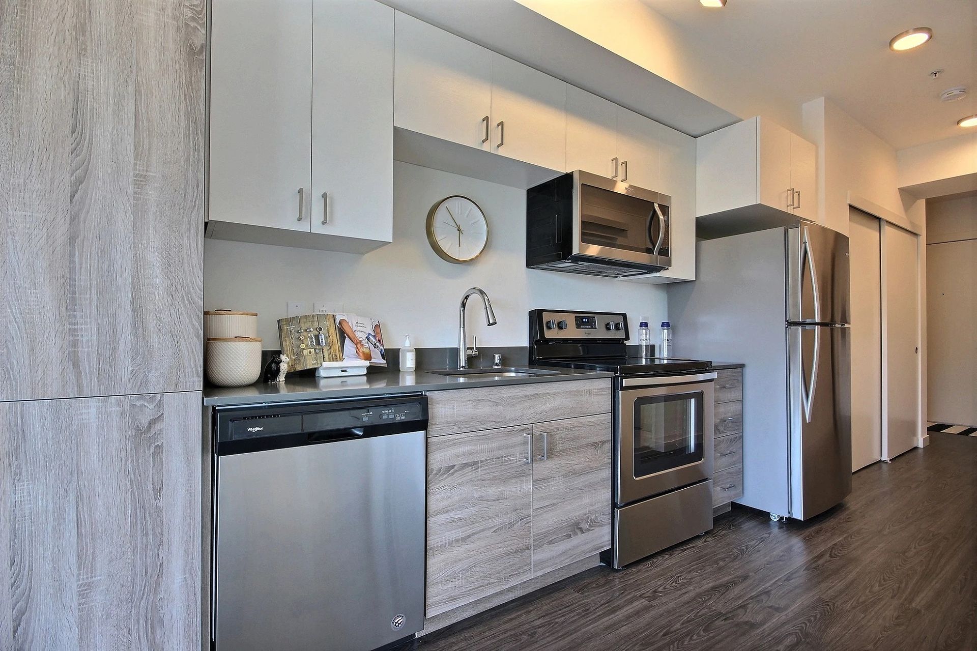 A kitchen with stainless steel appliances and wooden cabinets at CREW Apartments in Seattle, WA.