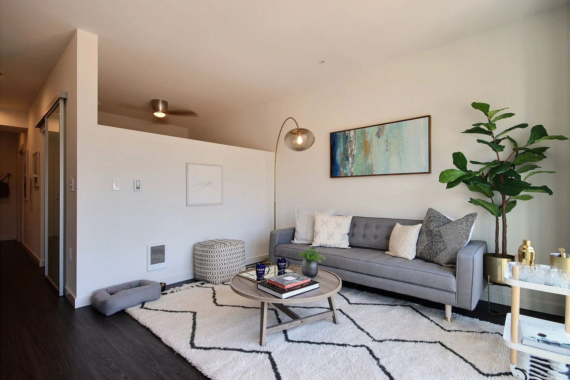 A living room with a couch , coffee table , and rug at CREW Apartments in Seattle, WA.