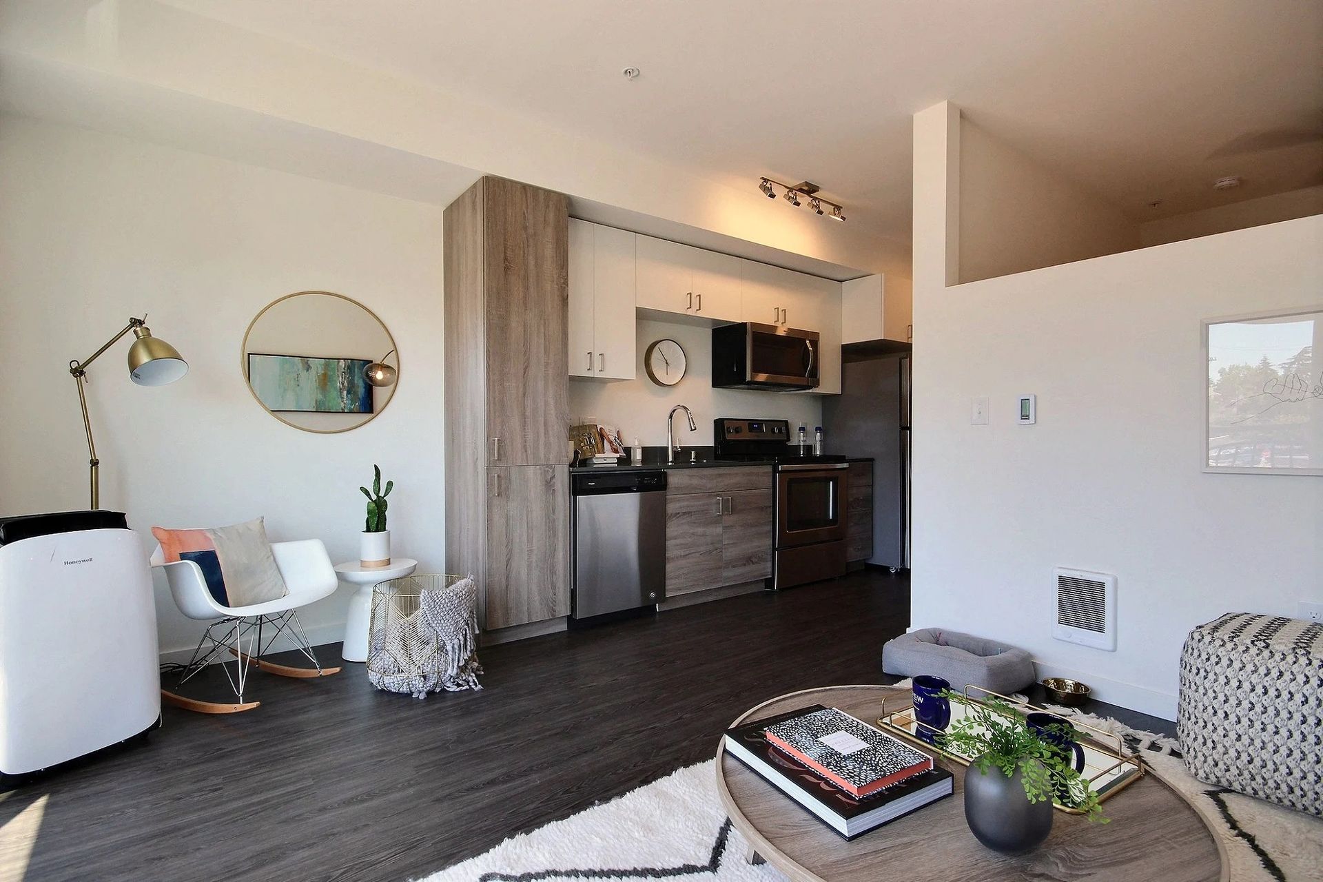 A living room with a table and chairs and a kitchen in the background at CREW Apartments in Seattle, WA.