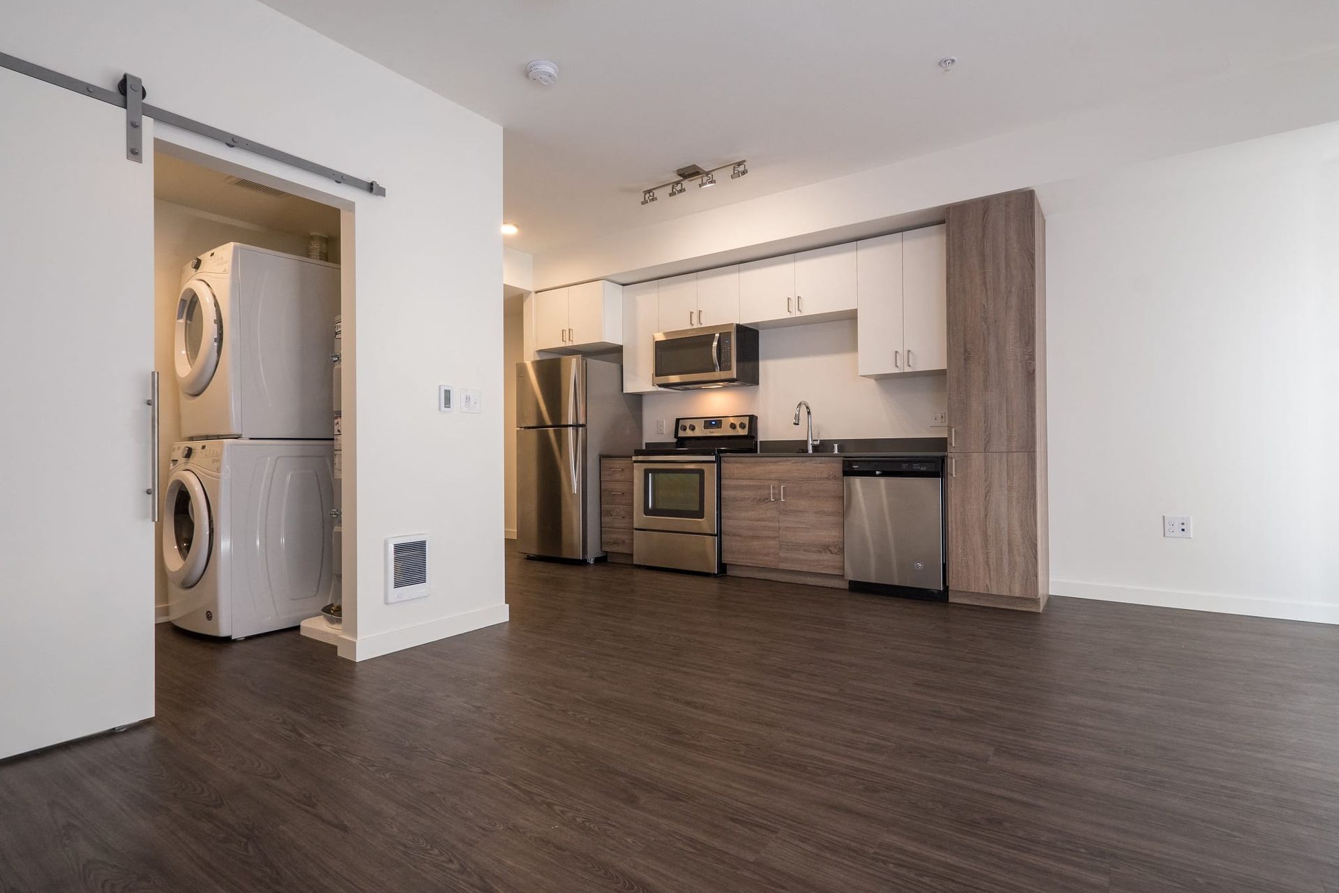 A kitchen with a washer and dryer stacked on top of each other at CREW Apartments in Seattle, WA.