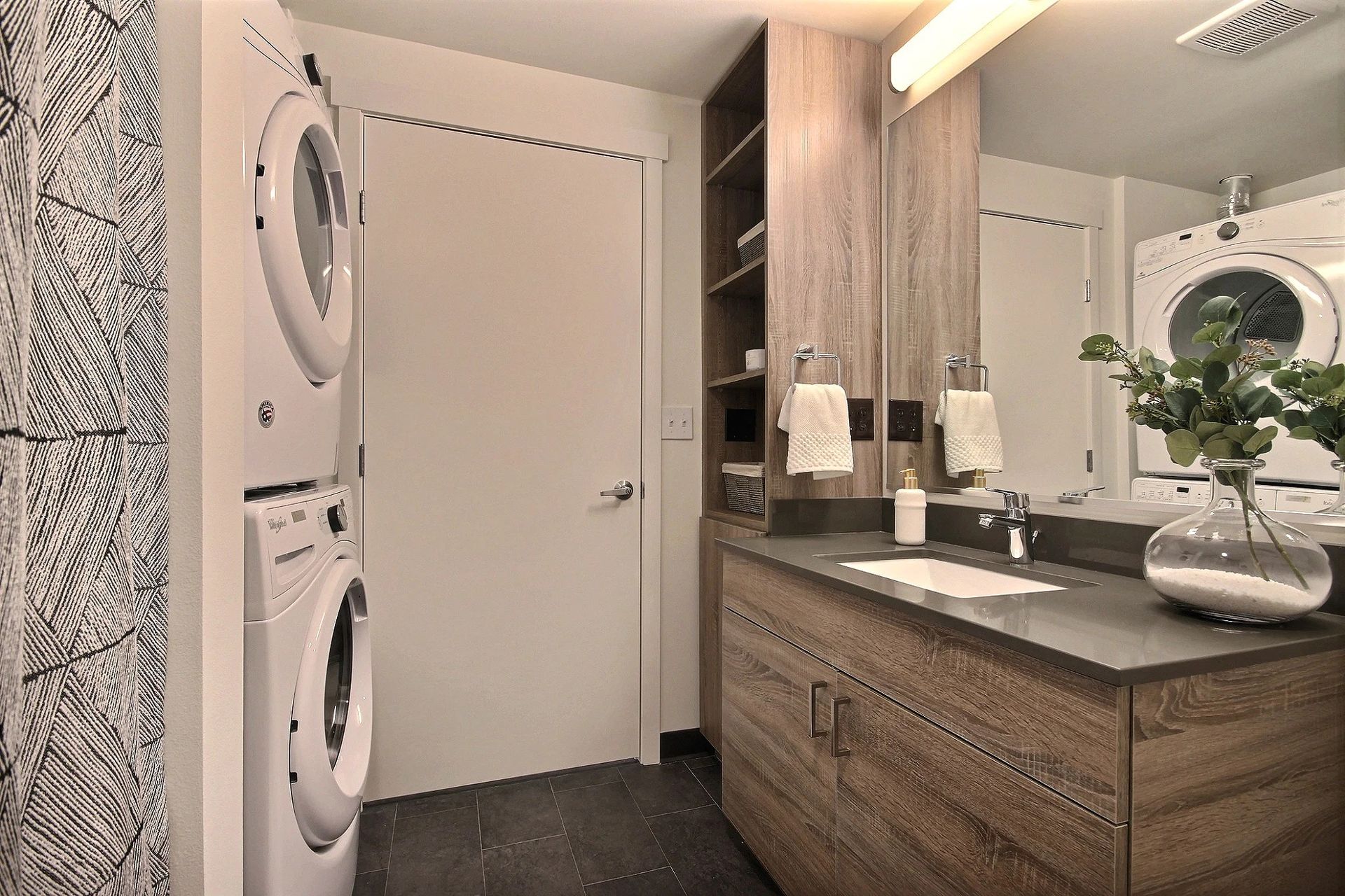 A bathroom with a sink , washer and dryer stacked on top of each other at CREW Apartments in Seattle, WA.