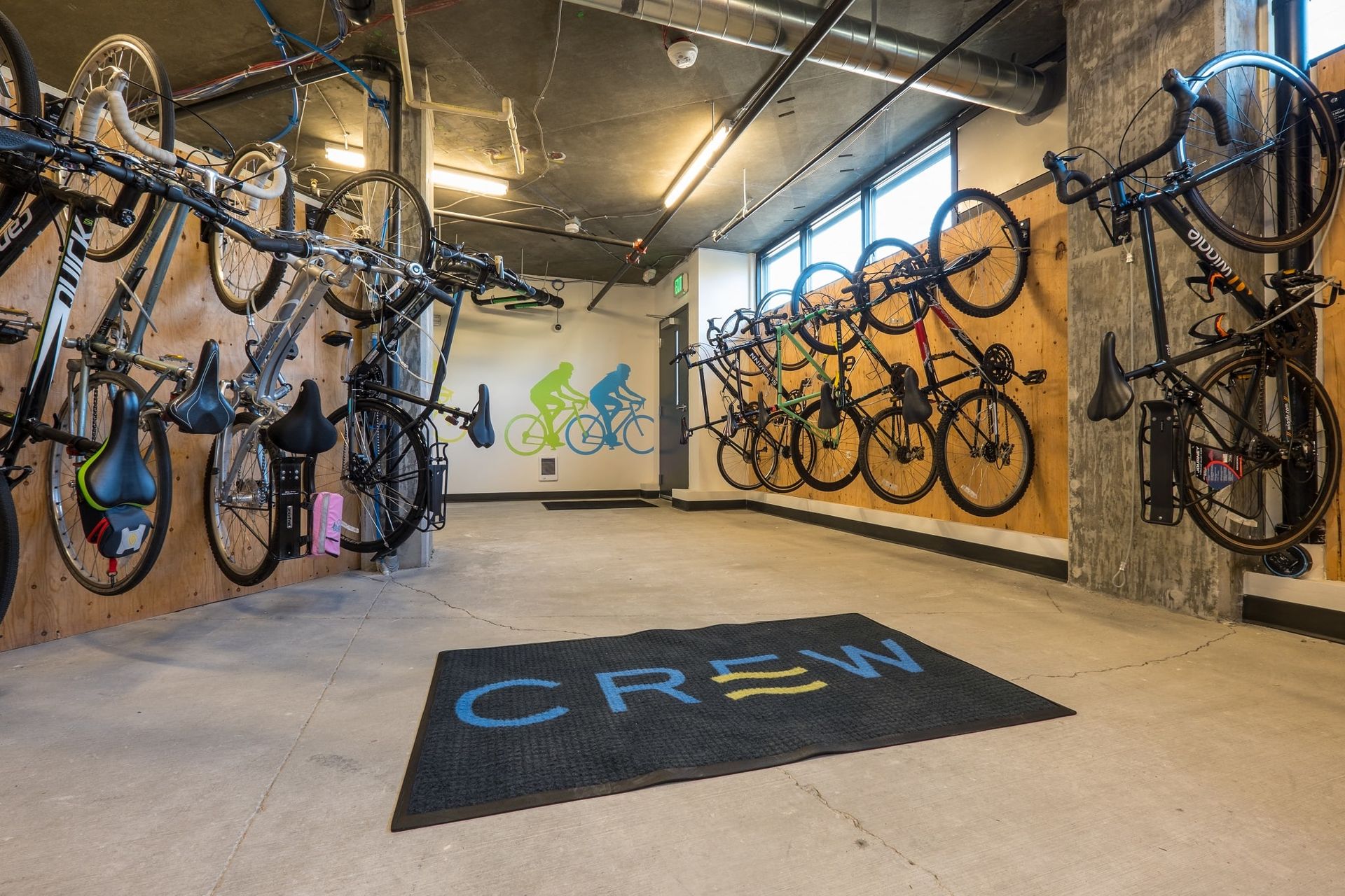 A room filled with lots of bikes and a mat that says crew at CREW Apartments in Seattle, WA.