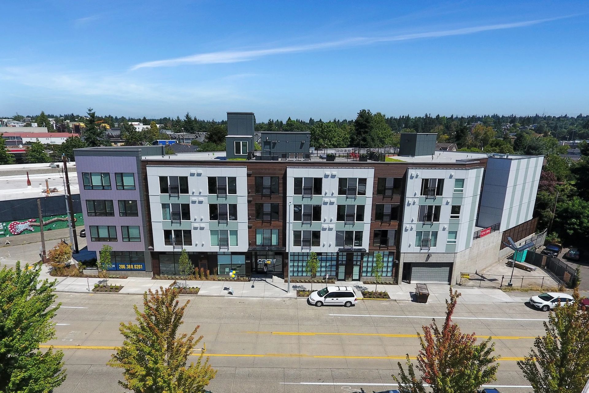 An aerial view of a large apartment building with cars parked in front of it at CREW Apartments in Seattle, WA.