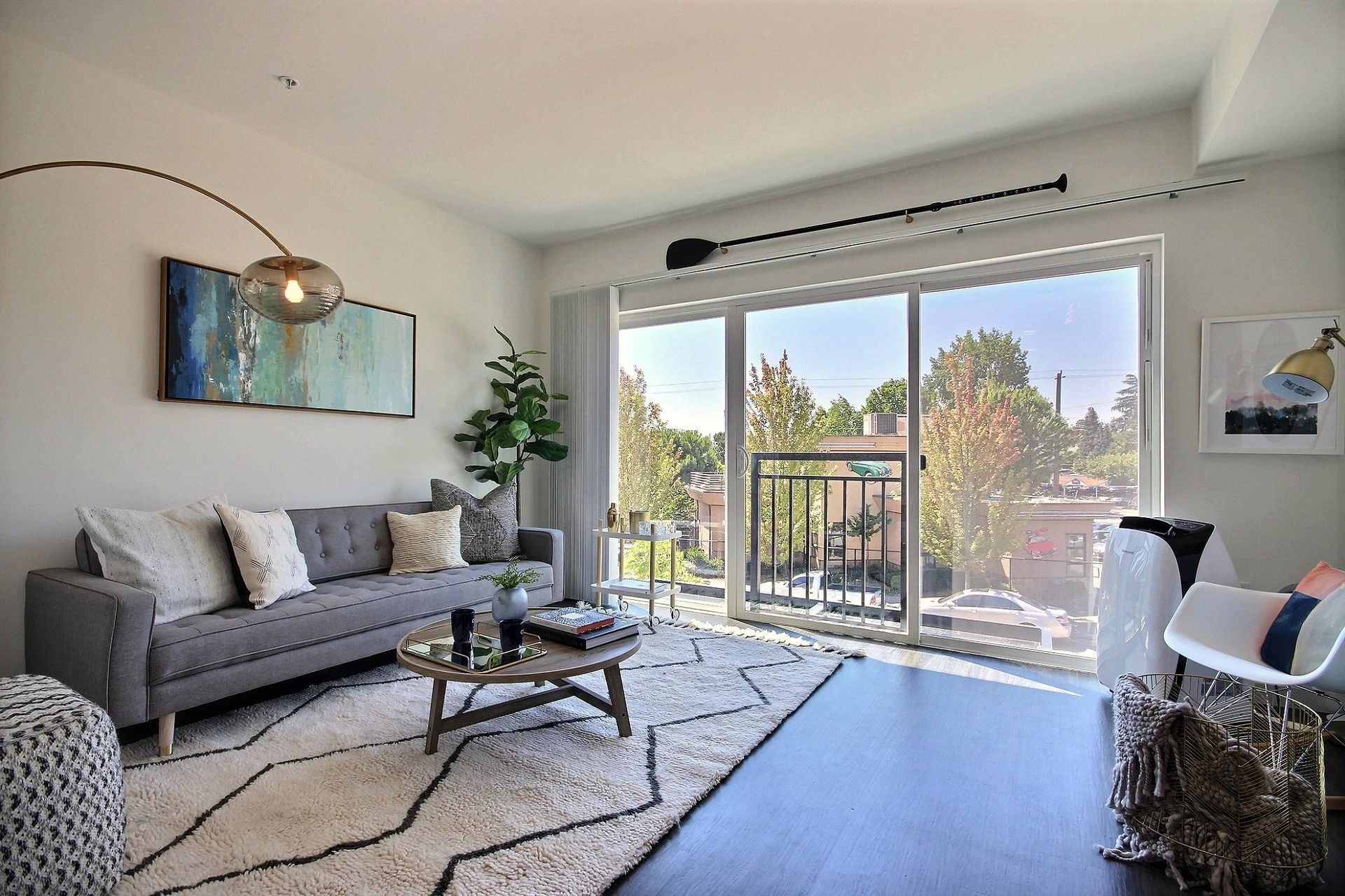 A living room with a couch , chair , coffee table and sliding glass doors at CREW Apartments in Seattle, WA.