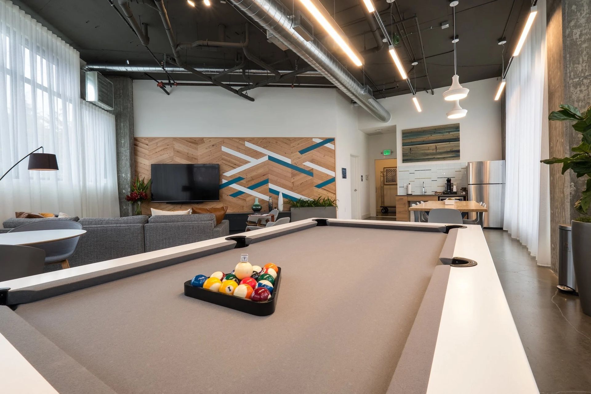 There is a pool table in the middle of the room at CREW Apartments in Seattle, WA.